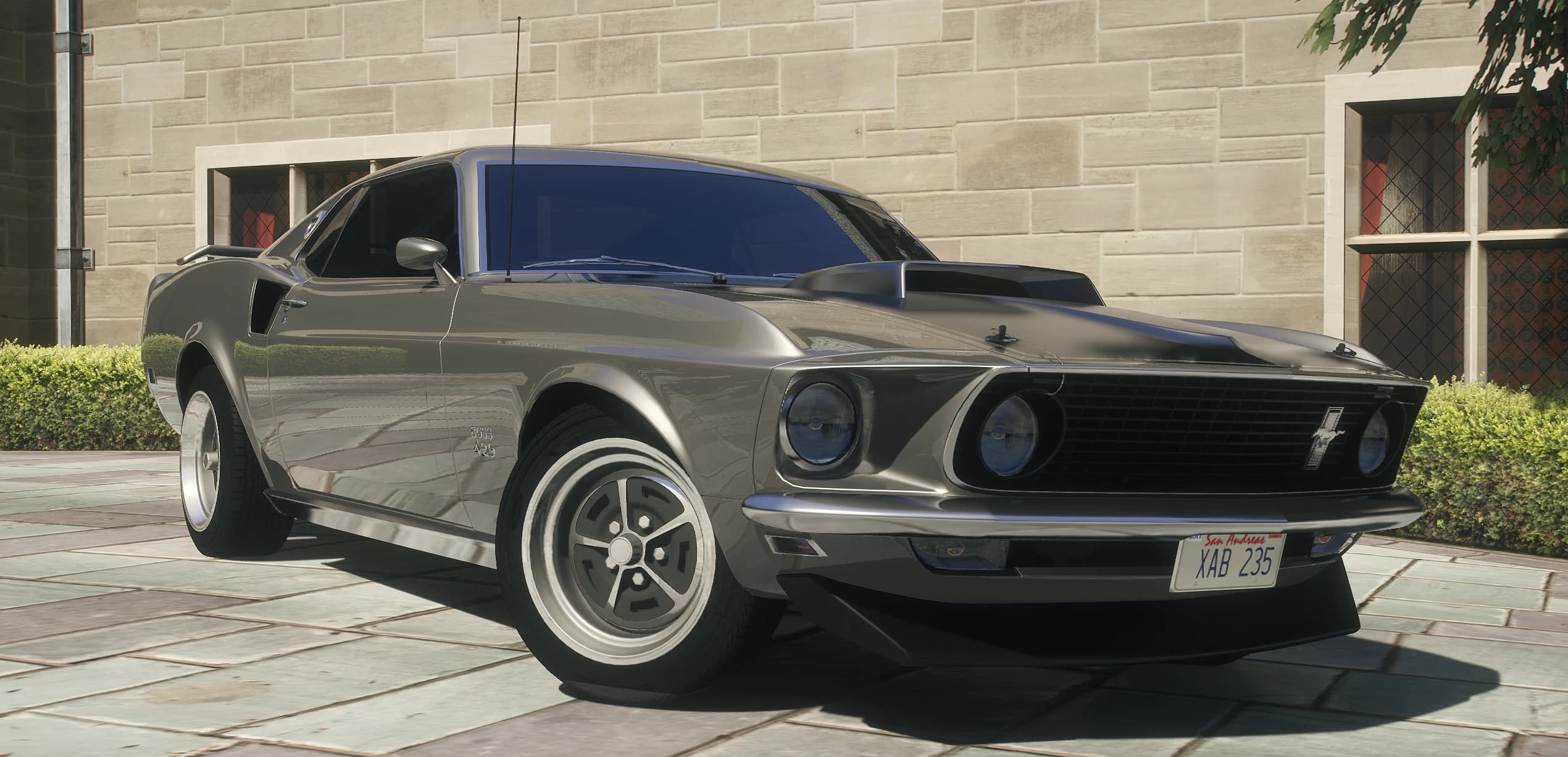 Front three quarter view of the gunmetal 1969 Mustang Boss 429 with its hood scoop outside a stone mansion