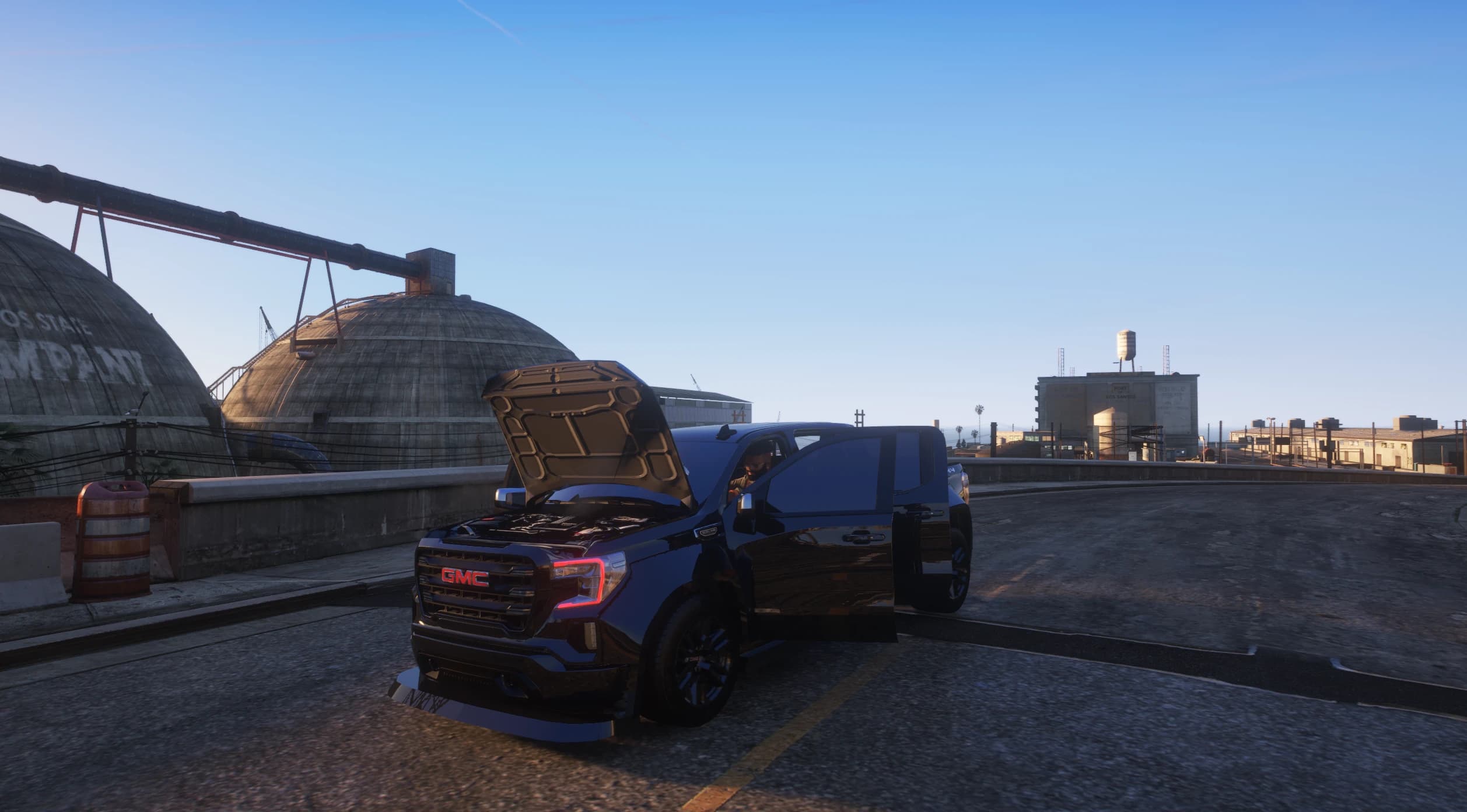 The GMC Sierra with its bonnet and driver door open next to the cement-plant domes, showing the modelled engine bay
