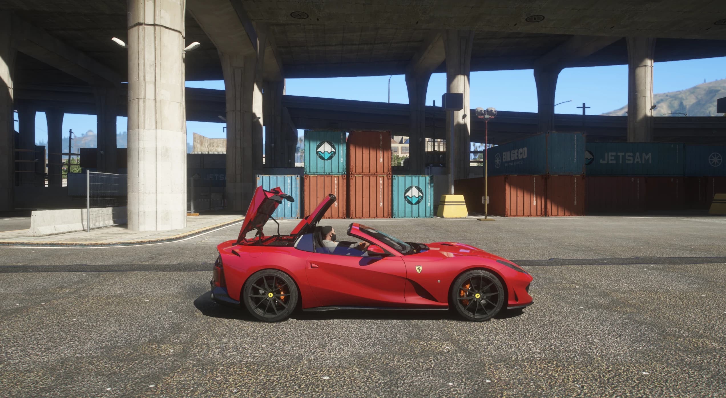 Side profile under a freeway overpass with the folding hardtop caught mid operation, panels lifted above the cabin