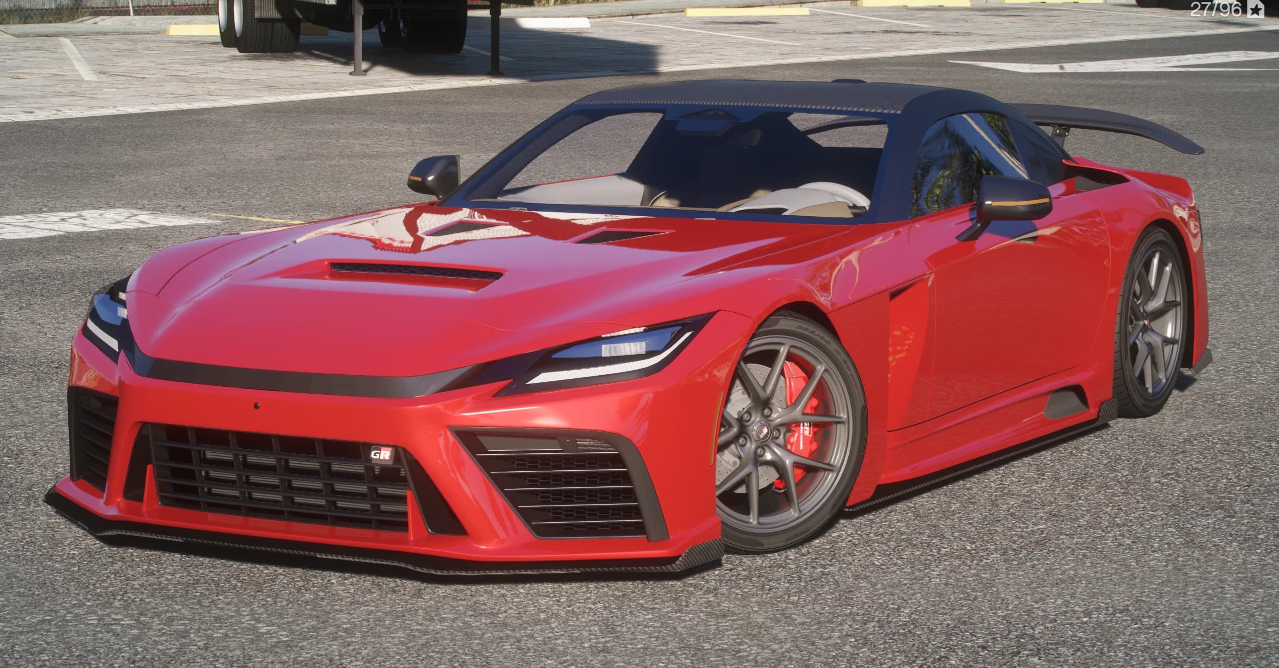 Red Toyota GR GT sports coupe with a carbon roof, big rear wing and grey multi-spoke wheels with red calipers, front three-quarter view in a parking lot