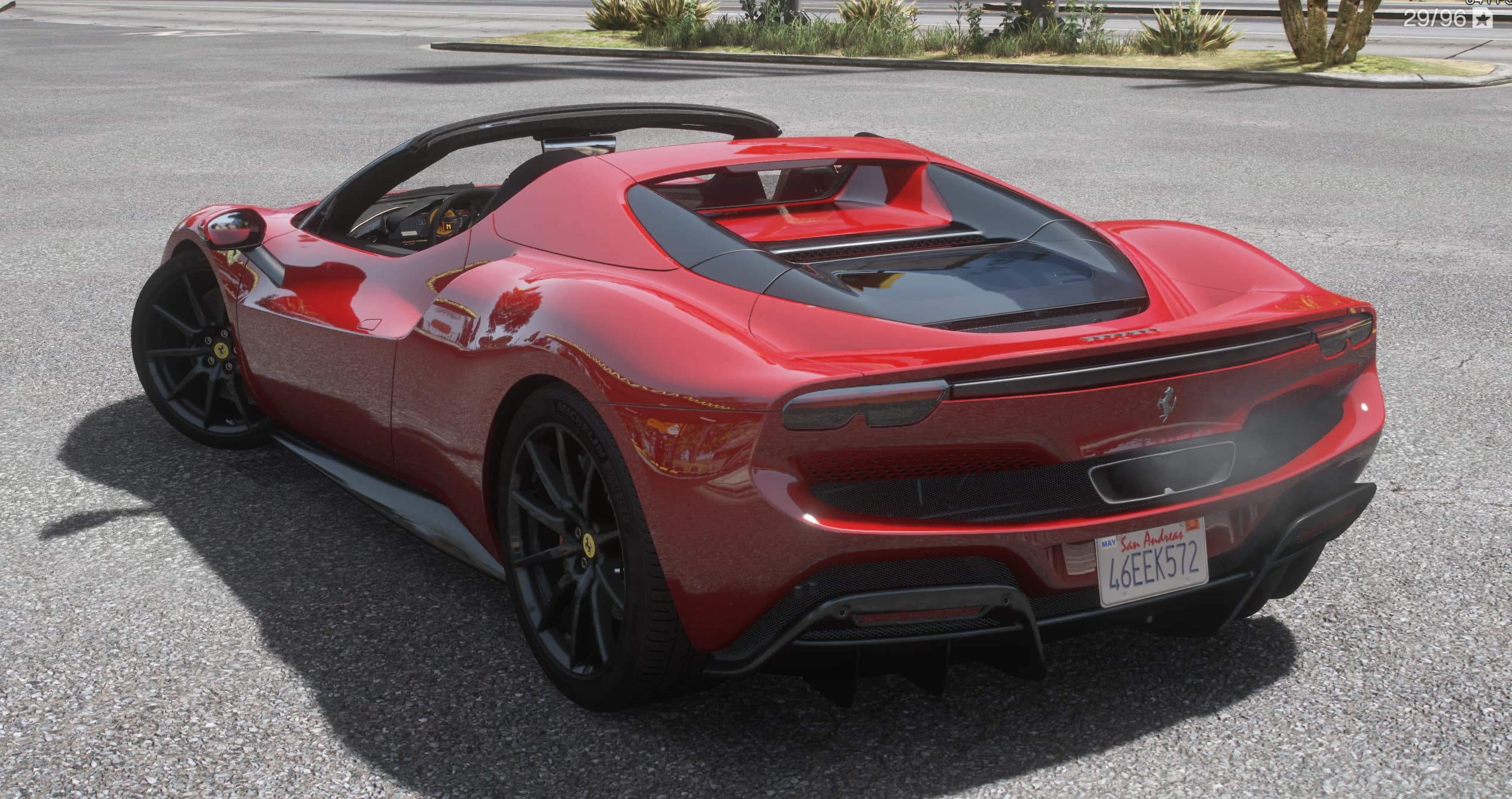Rear three-quarter of the red 296 GTS with the roof stowed, showing the glass engine cover, twin round taillights and black diffuser