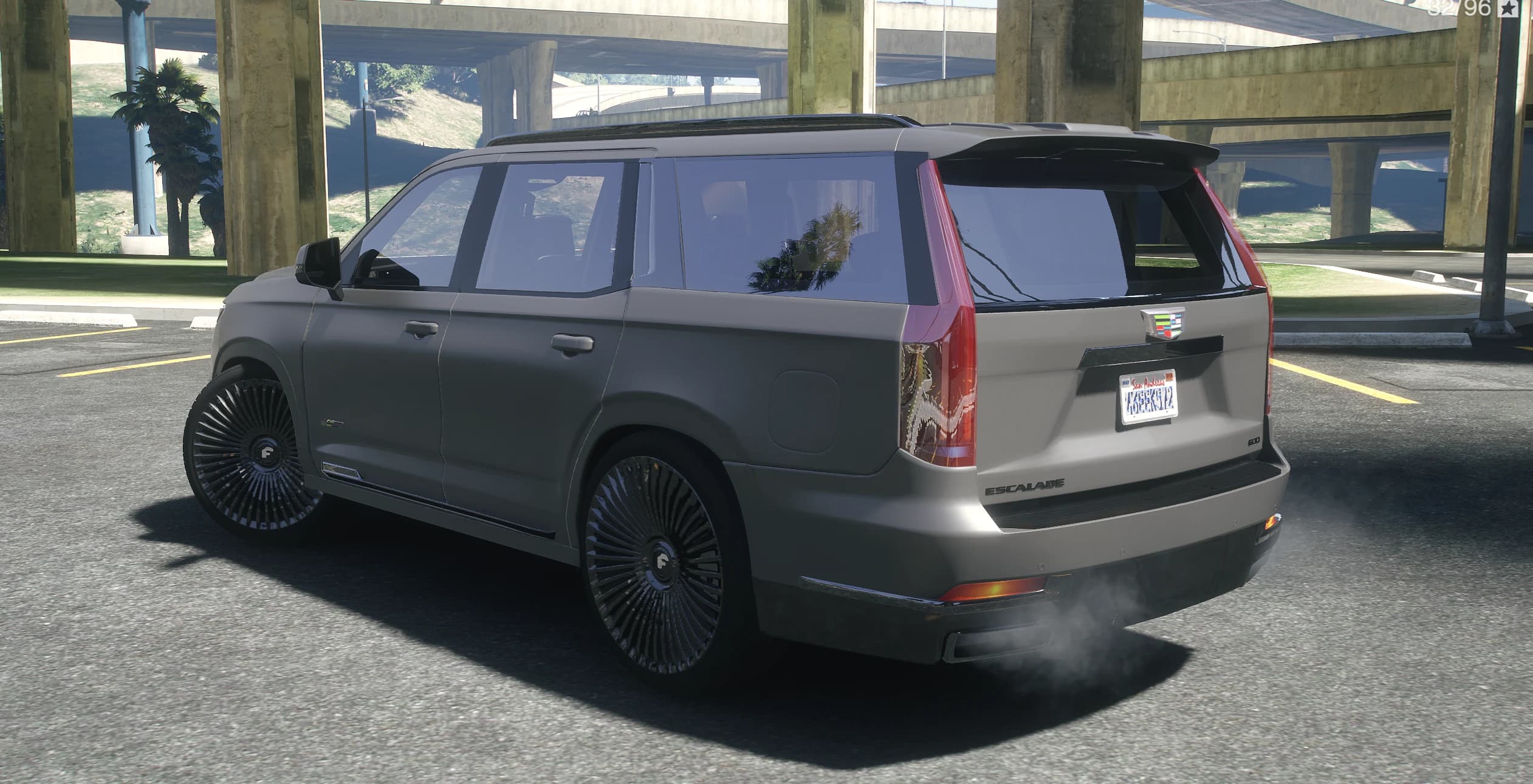 Rear view of the Escalade with the vertical taillights, roof spoiler and smoke from the exhaust