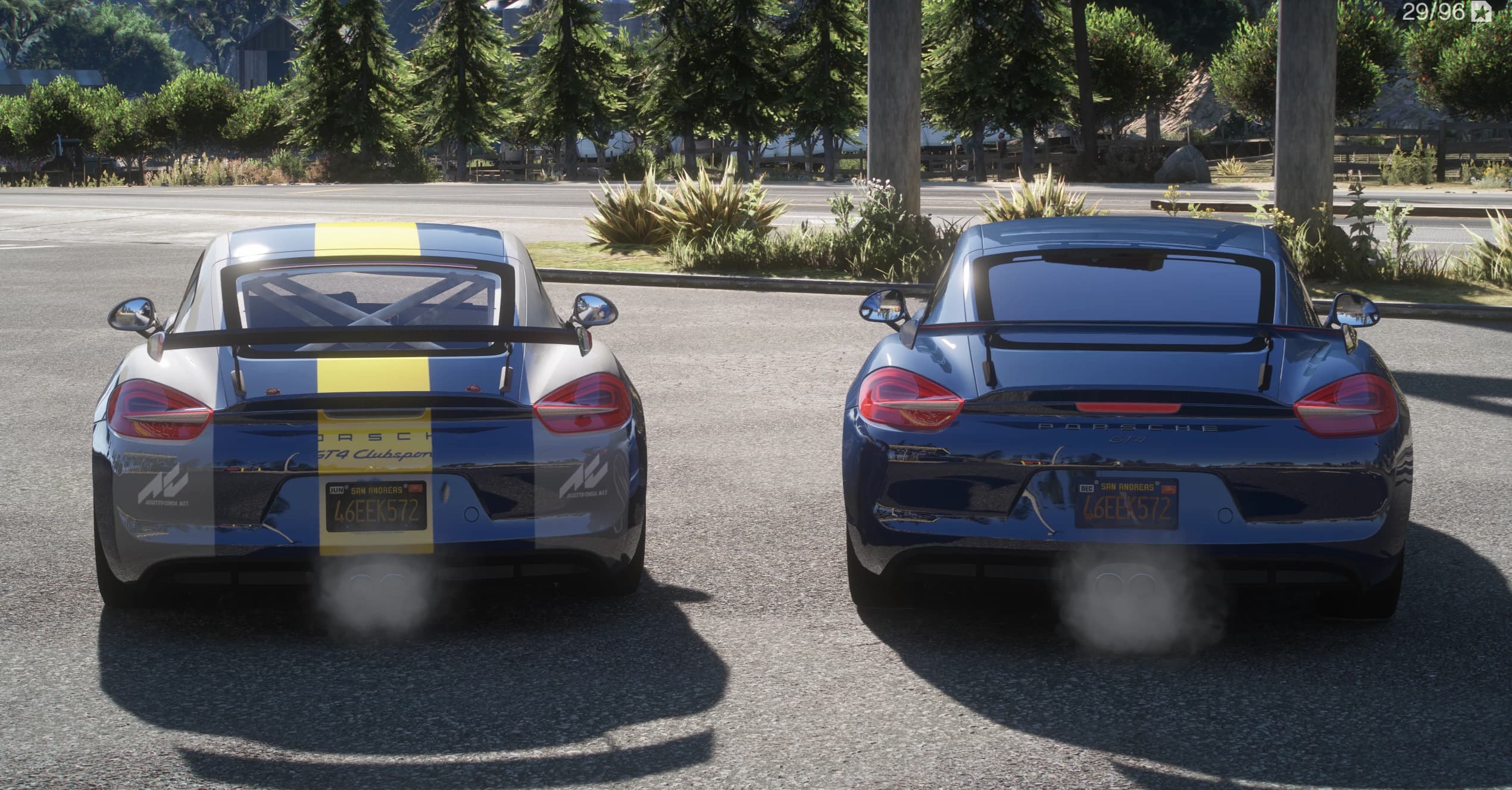 Rear view of both Caymans, the GT4 Clubsport wearing a yellow racing stripe and GT4 Clubsport decals, the road GT4 in dark blue with a fixed wing