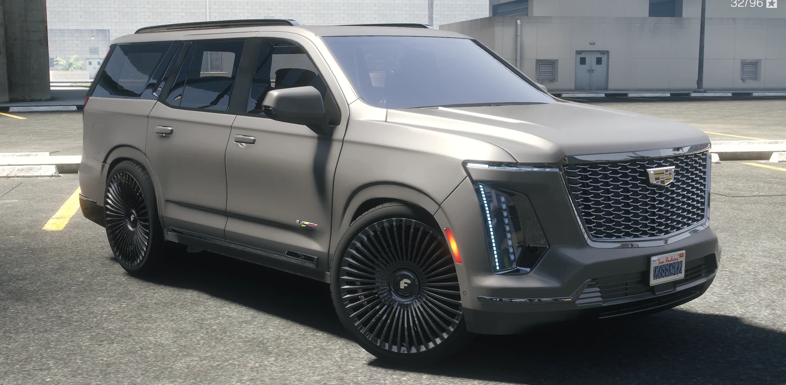 Front three quarter view of the matte gray 2025 Escalade with the lit grille and tall multi spoke donk wheels