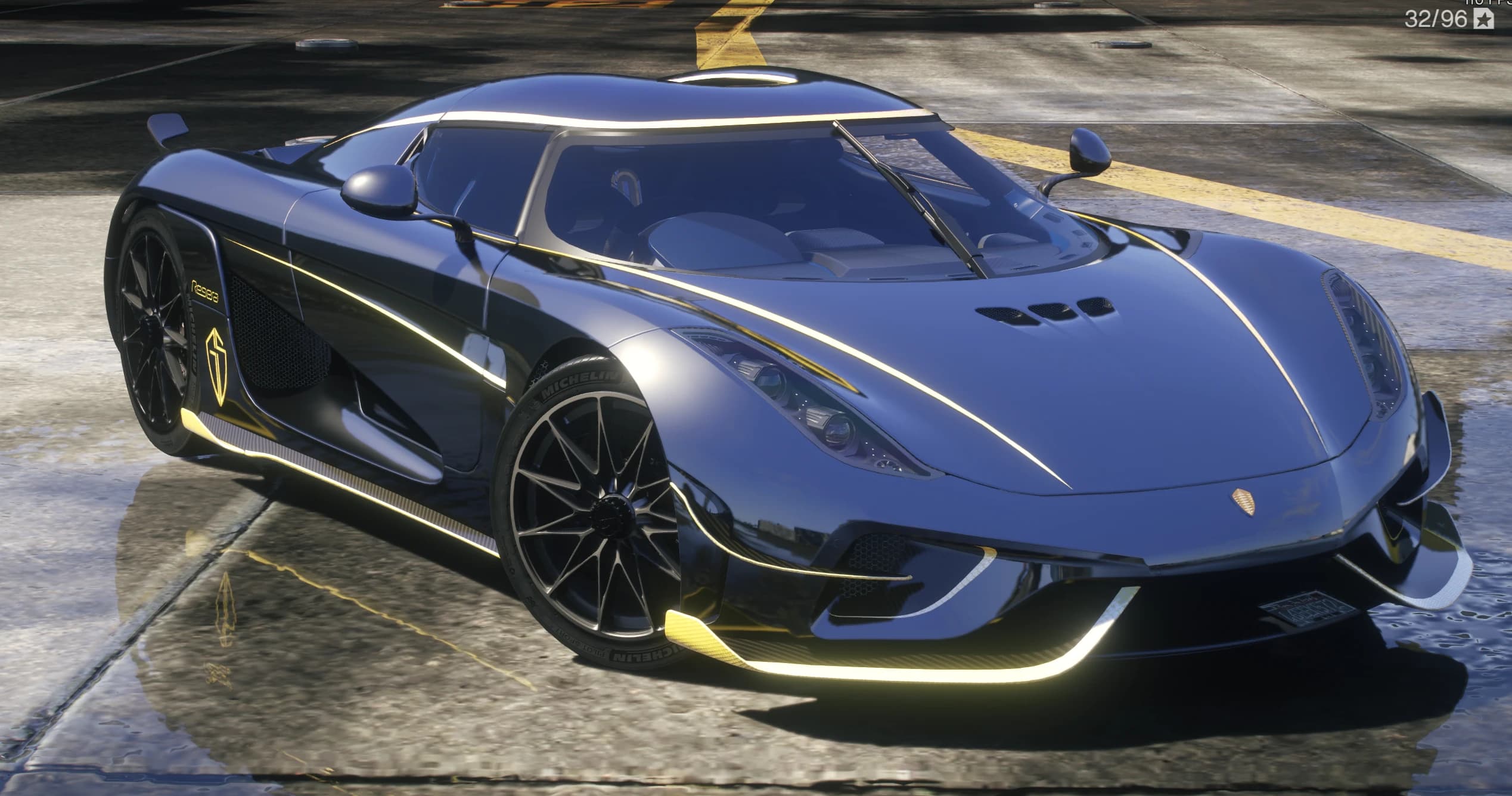 Front three quarter view of the dark blue Regera with gold pinstripes, the gold ghost shield and Michelin tires