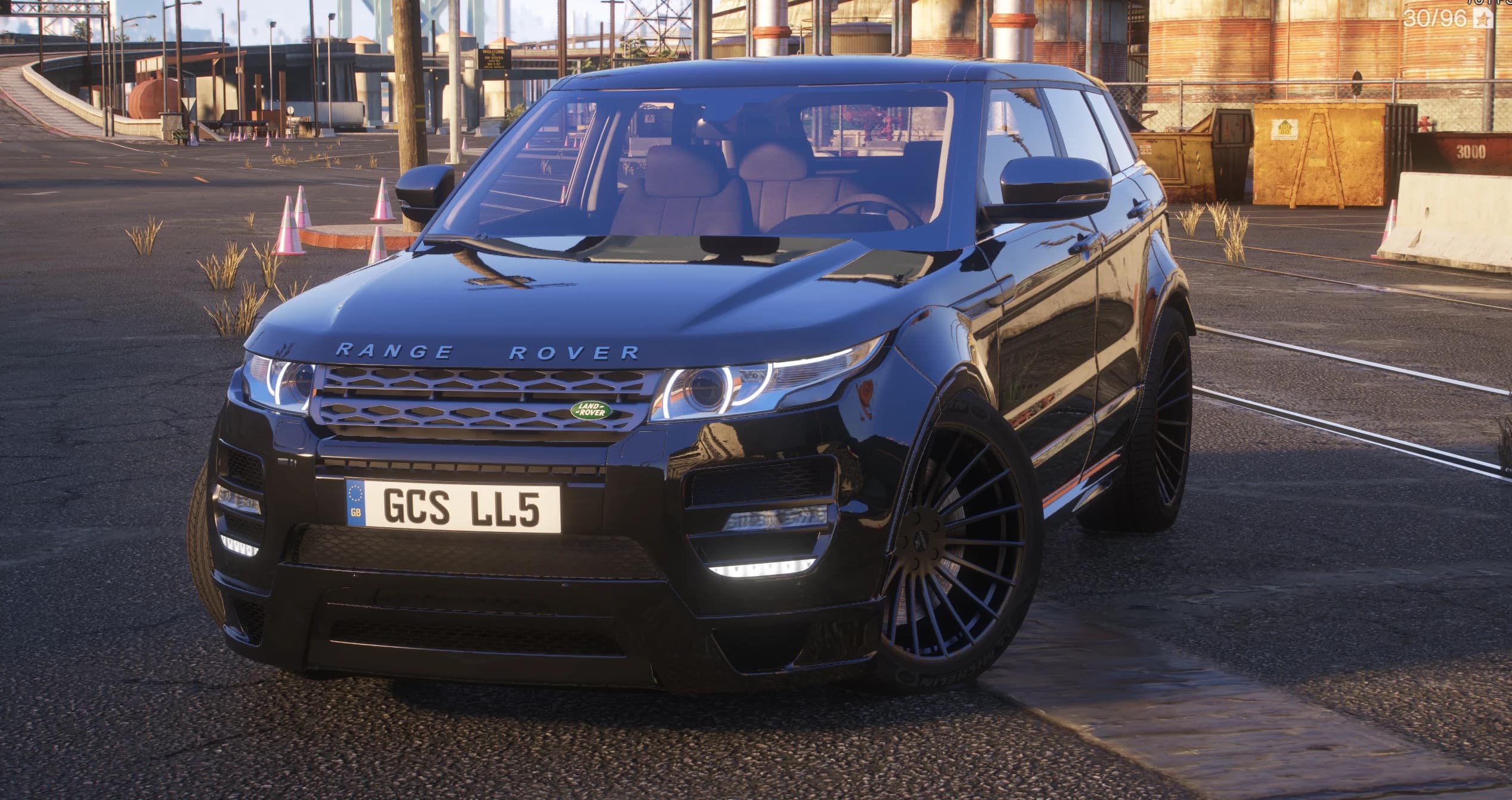 Front view of the black Range Rover Evoque with the Hamann wide-body kit, halo headlights and multi-spoke black wheels in an industrial yard