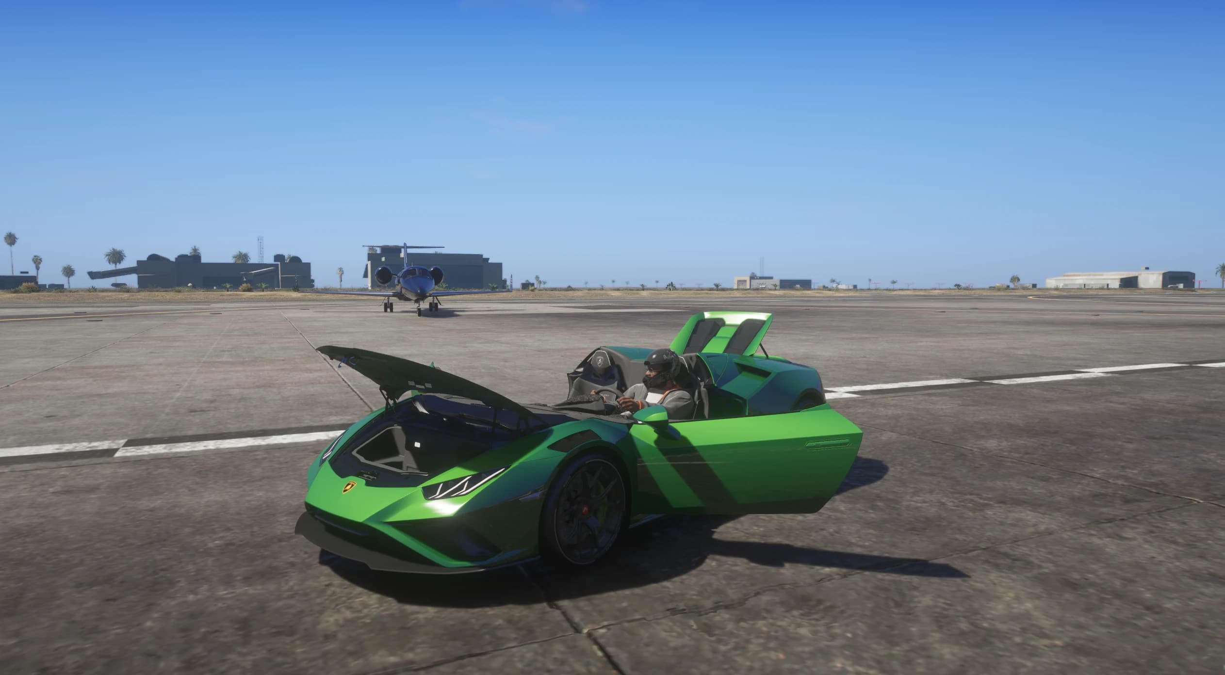 The open speedster on a runway with the front trunk lid raised, both doors open and the driver sitting in the exposed cockpit