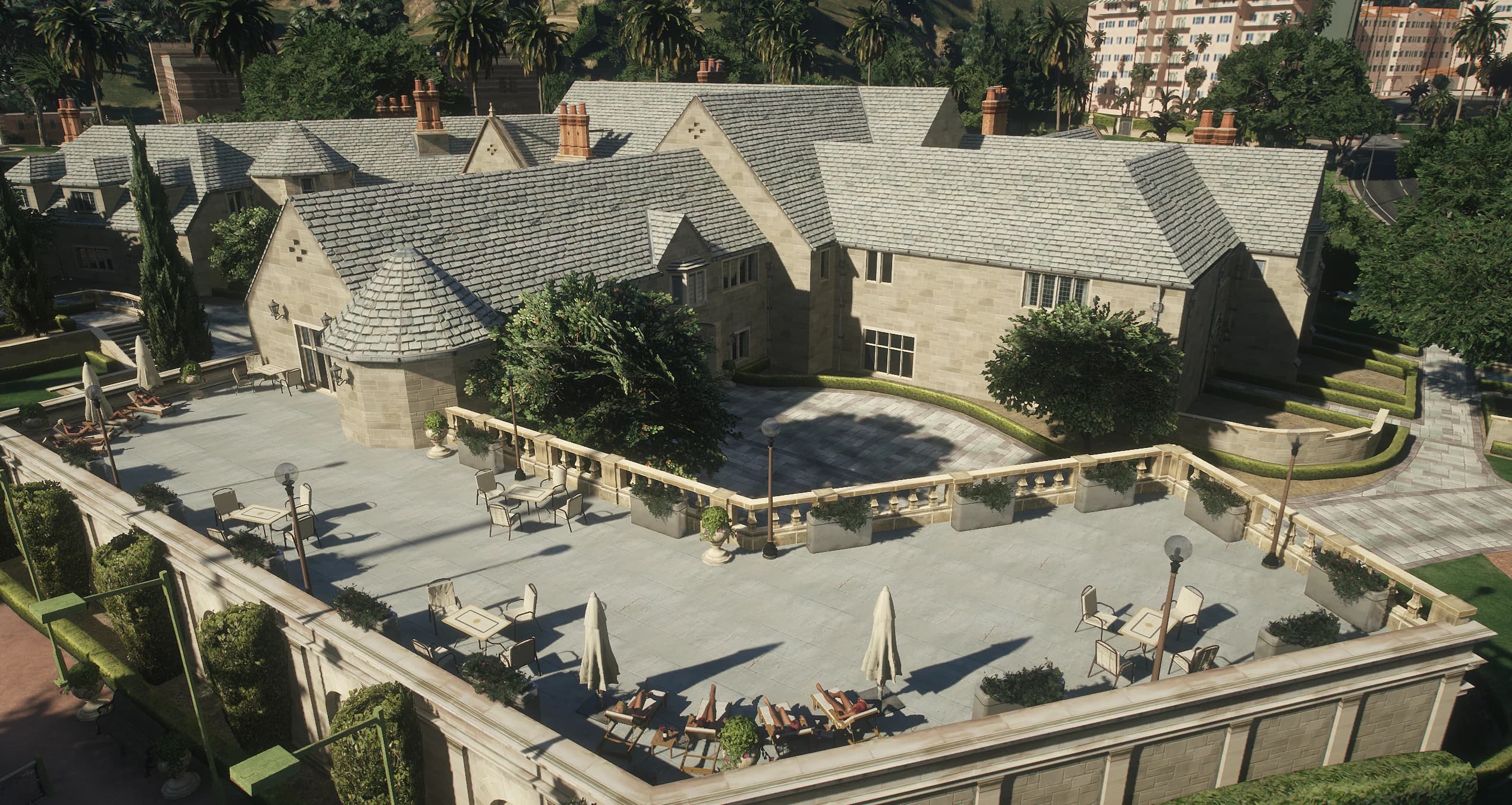 Walled sun terrace with loungers, tables and parasols beside the mansion