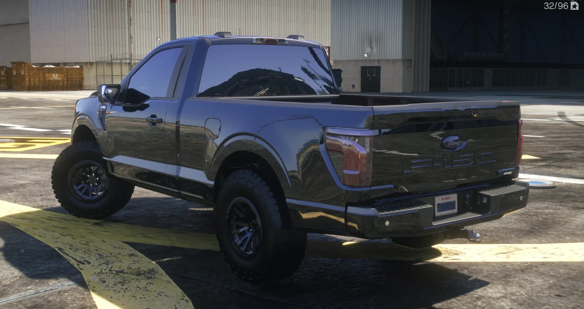 Rear three quarter view showing the F-150 stamped tailgate, step bumper with tow hitch and the lifted stance on chunky tyres