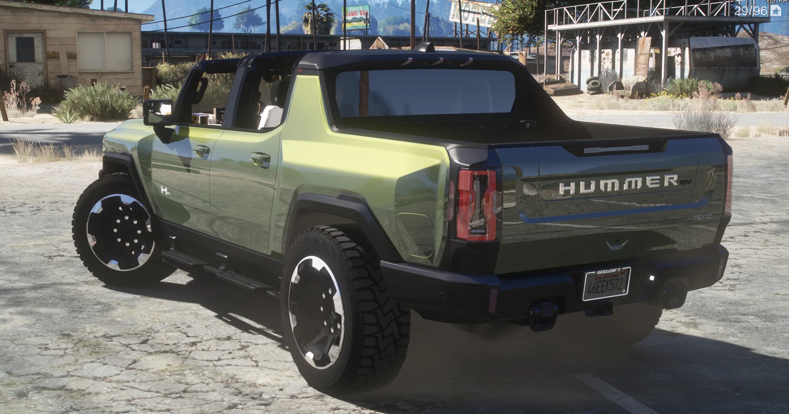 Rear three-quarter with the HUMMER EV lettering on the tailgate and a San Andreas plate, in a desert motel area