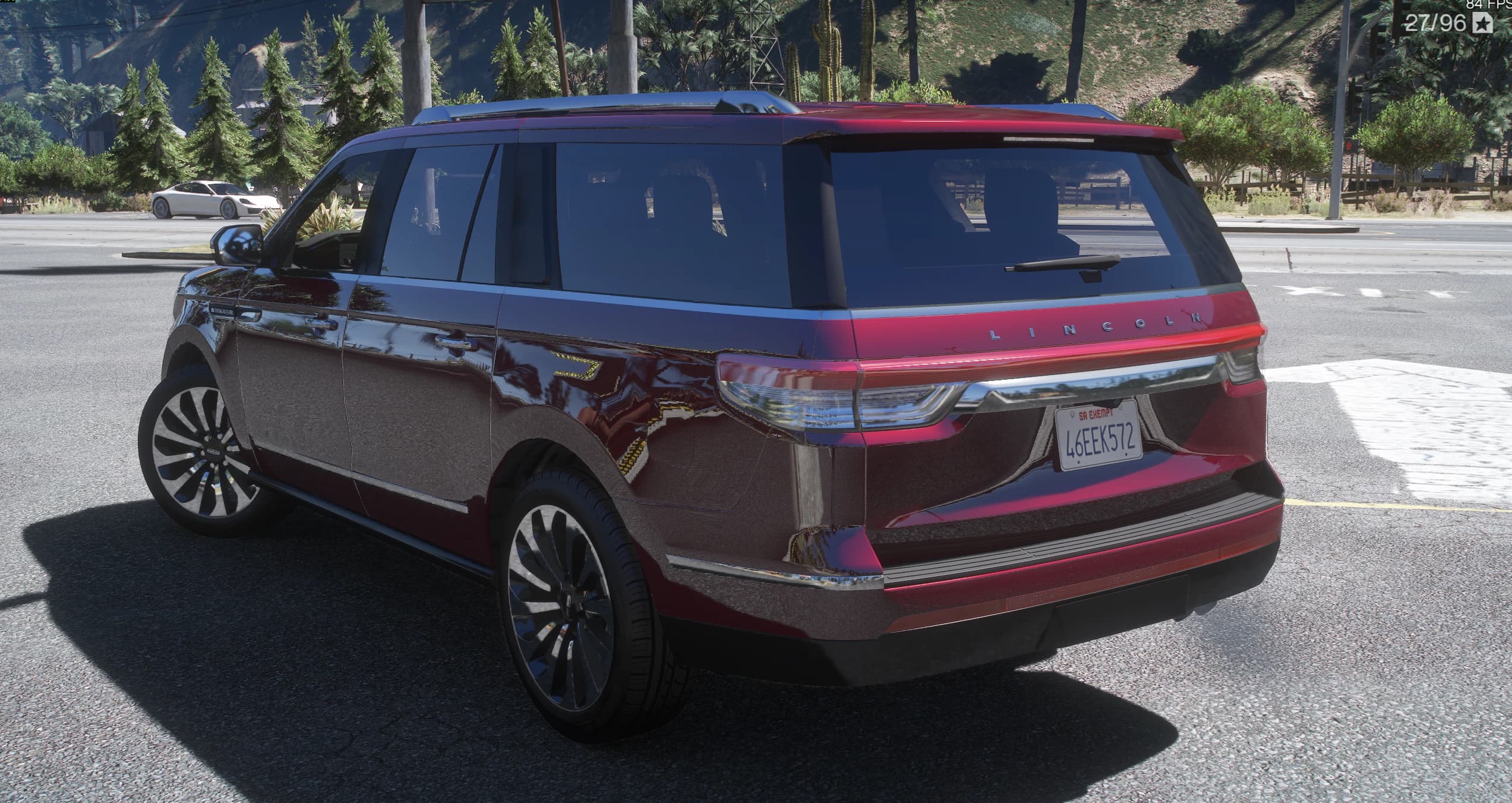Rear three-quarter of the red Navigator with the LINCOLN lettering spelled out across the tailgate, the full-width tail light bar, the roof spoiler and chrome trim along the windows