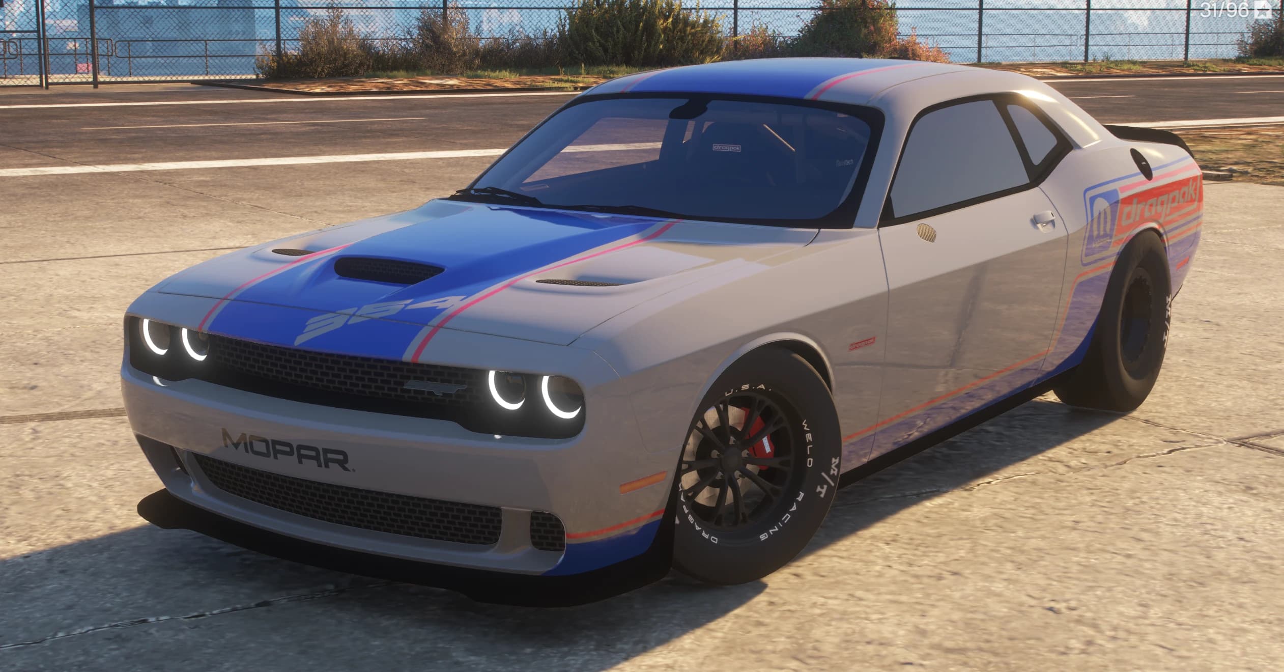 Front three quarter view of the silver Challenger Dragpak with a blue stripe over the hood, 354 graphic, MOPAR nose lettering and skinny front drag wheels