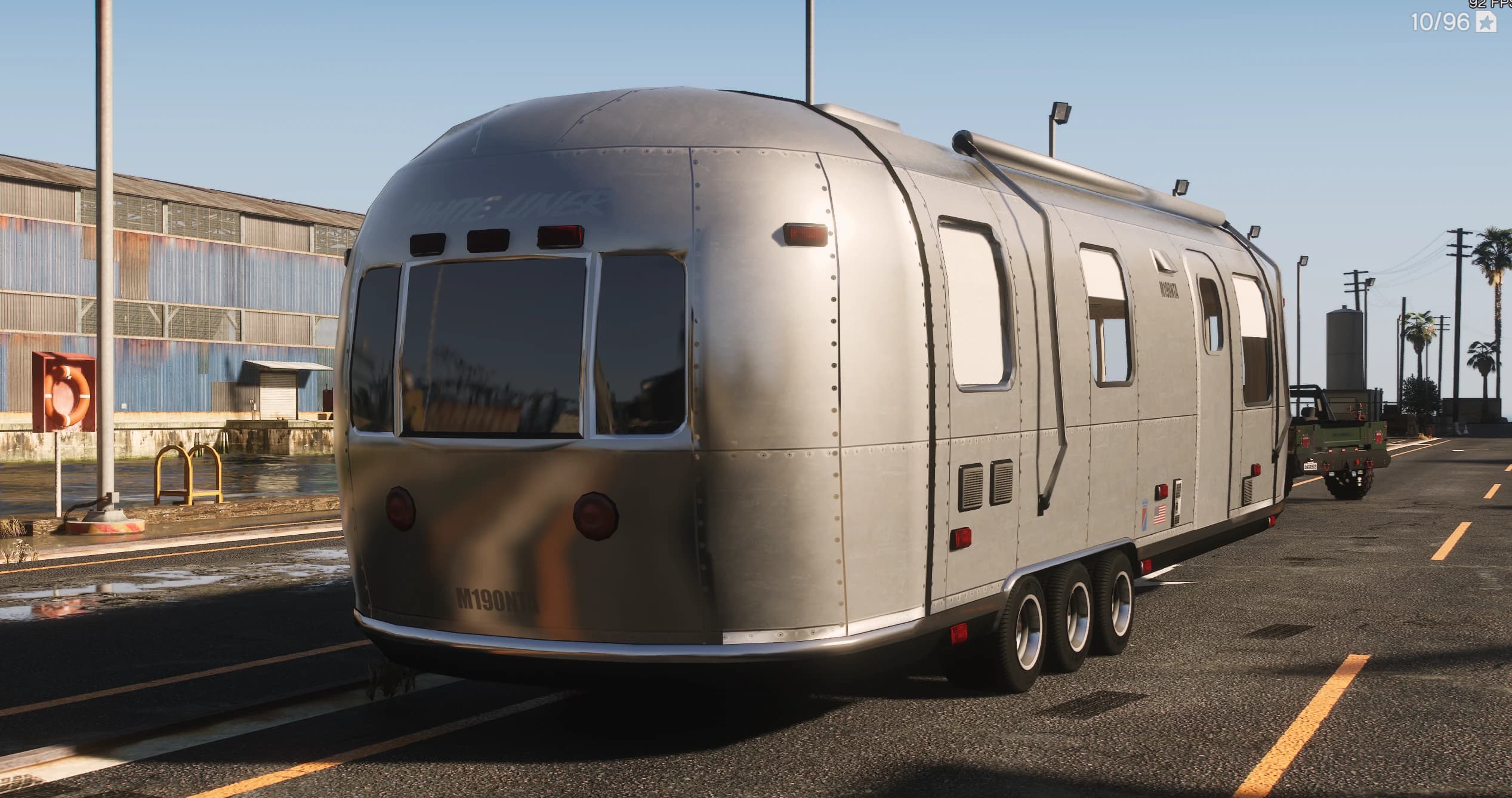 Rear three-quarter of the silver White Liner trailer showing the rounded end, tail lights and the M190NTB plate near a warehouse