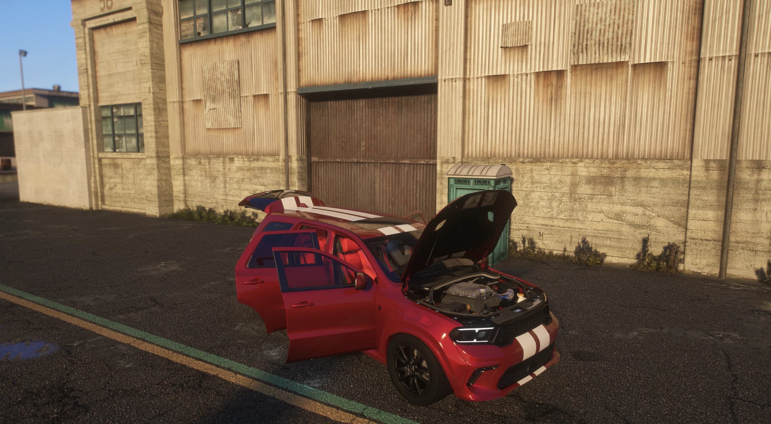 Red Durango with the hood and both left doors open in front of a weathered warehouse, revealing the supercharged HEMI engine bay and the red-and-black interior