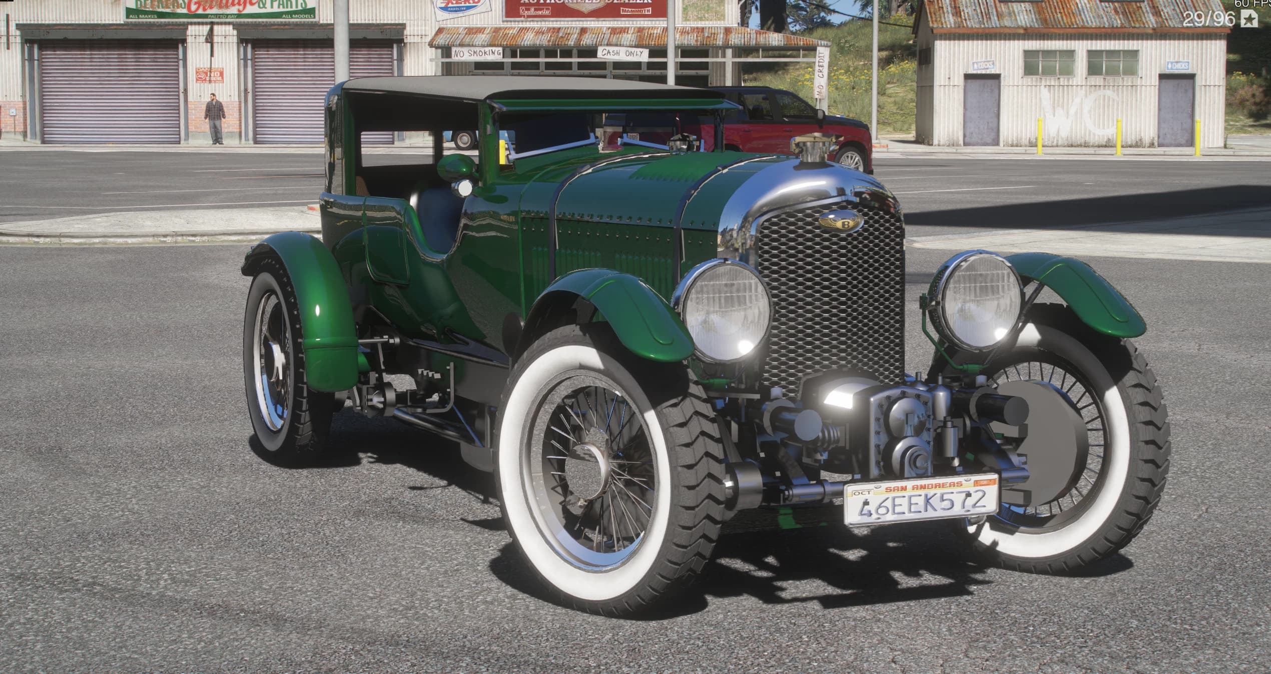 Front three-quarter of the green Bentley with the black fabric roof raised, showing the external valvetrain and the twin round headlights