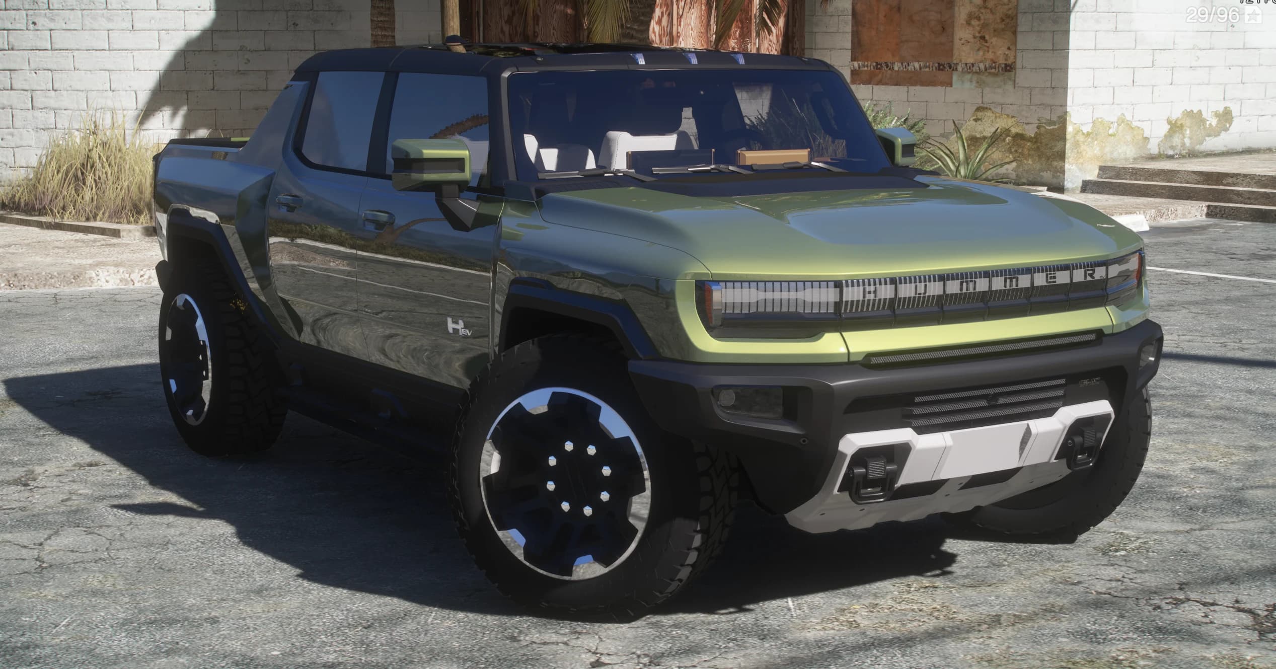 Close front three-quarter of the Hummer EV showing the illuminated HUMMER grille, open-air cab and white seats