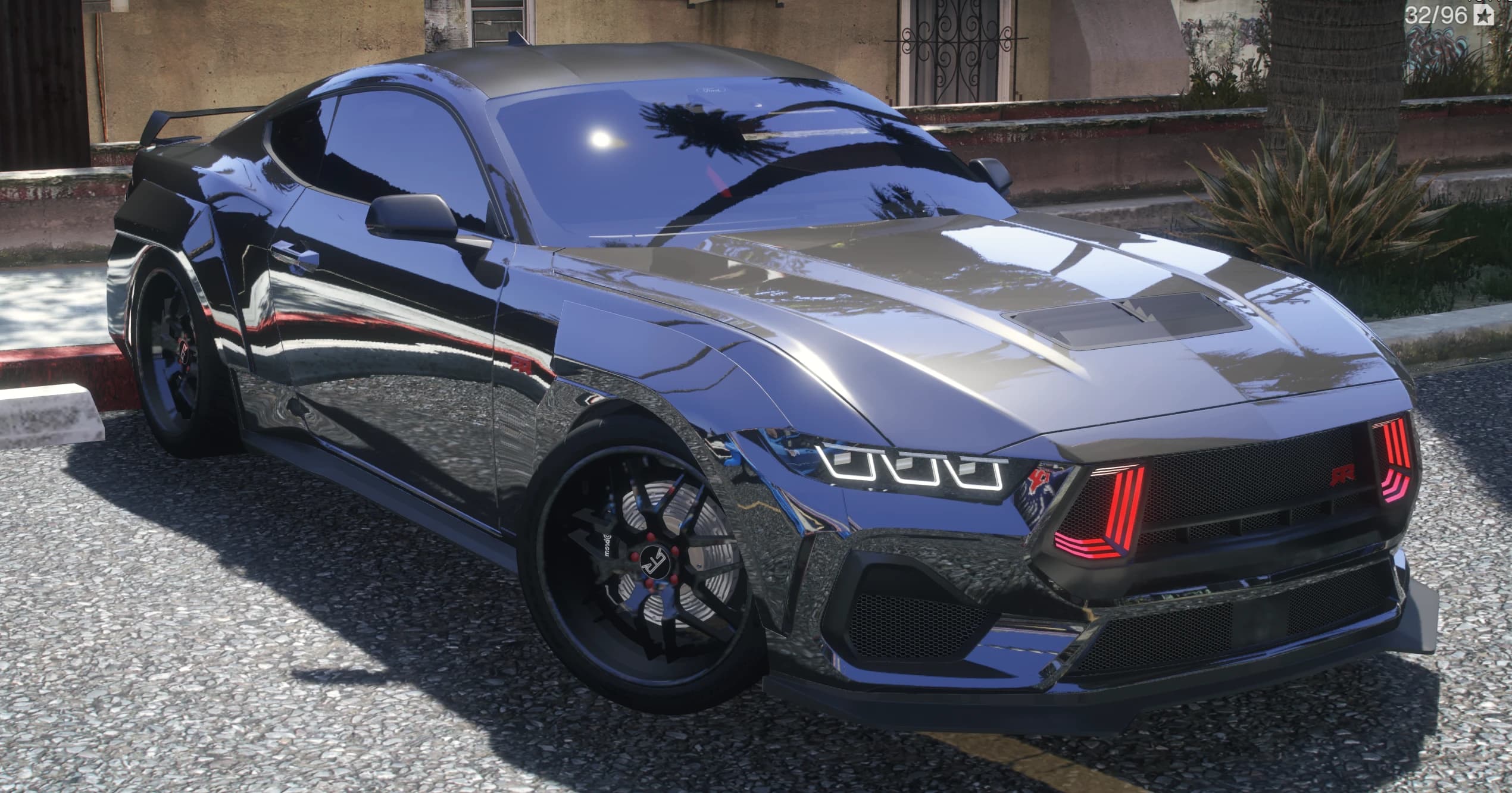 Front three quarter view of the graphite Mustang RTR with the red lit RTR grille, hood vents and widebody flares