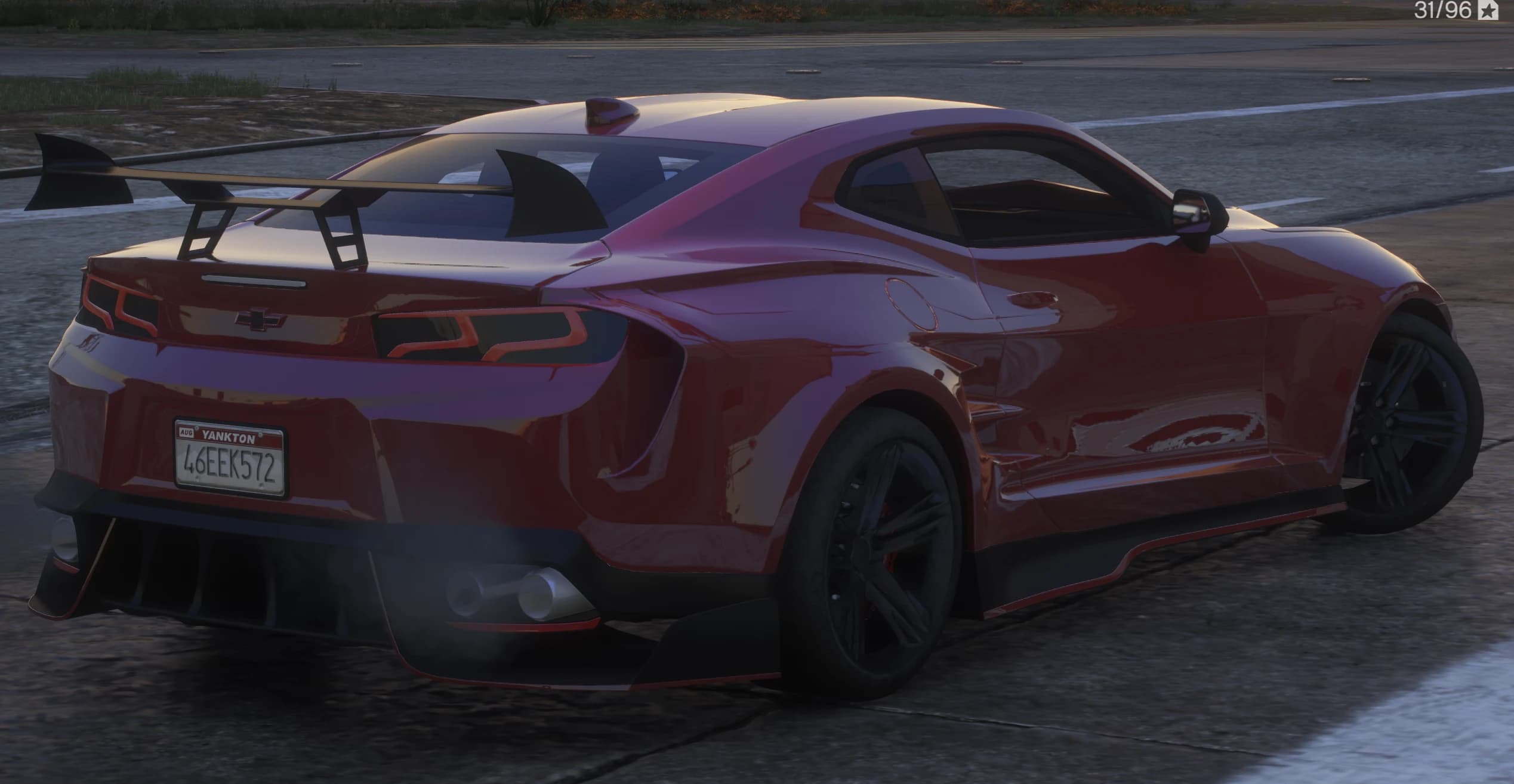 Rear three quarter view showing the tall GT wing on finned struts, dark taillights outlined in red and the finned diffuser