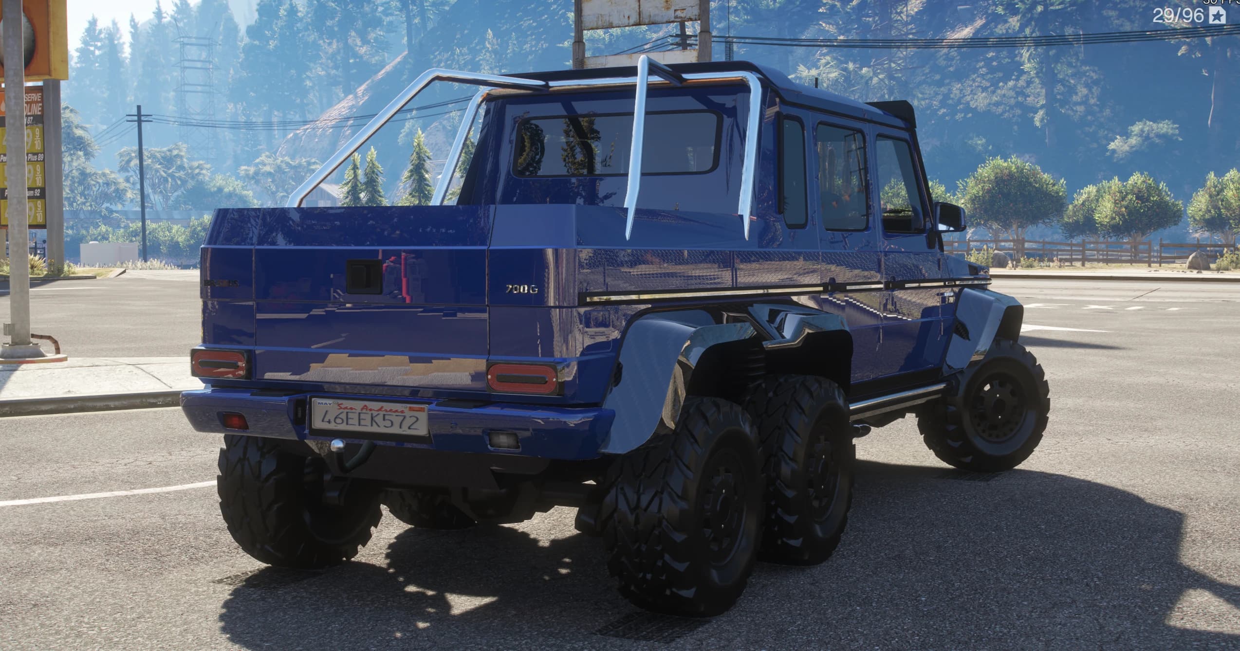 Rear three-quarter of the blue G63 6x6 showing the pickup bed, the 700G badge, the roll bar and the twin rear axles
