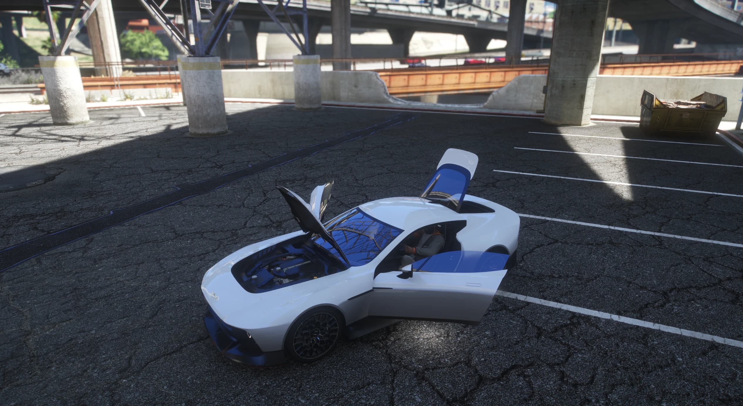 Overhead view with the clamshell hood open over the V12, driver door open and the rear hatch raised in a parking lot
