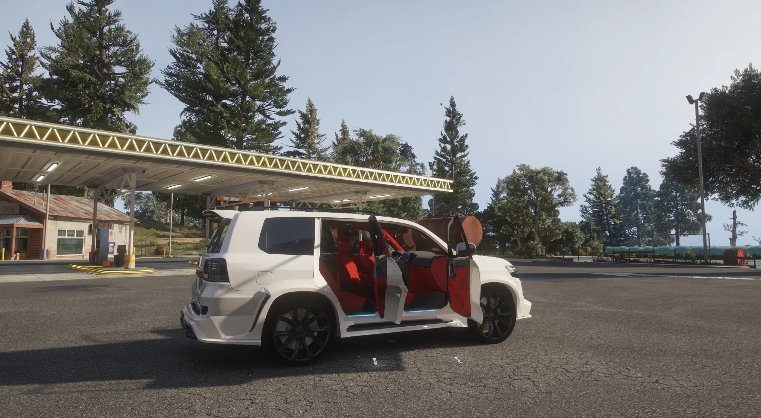 Side view of the Land Cruiser with all doors and the tailgate open, revealing the red leather interior, at a petrol station