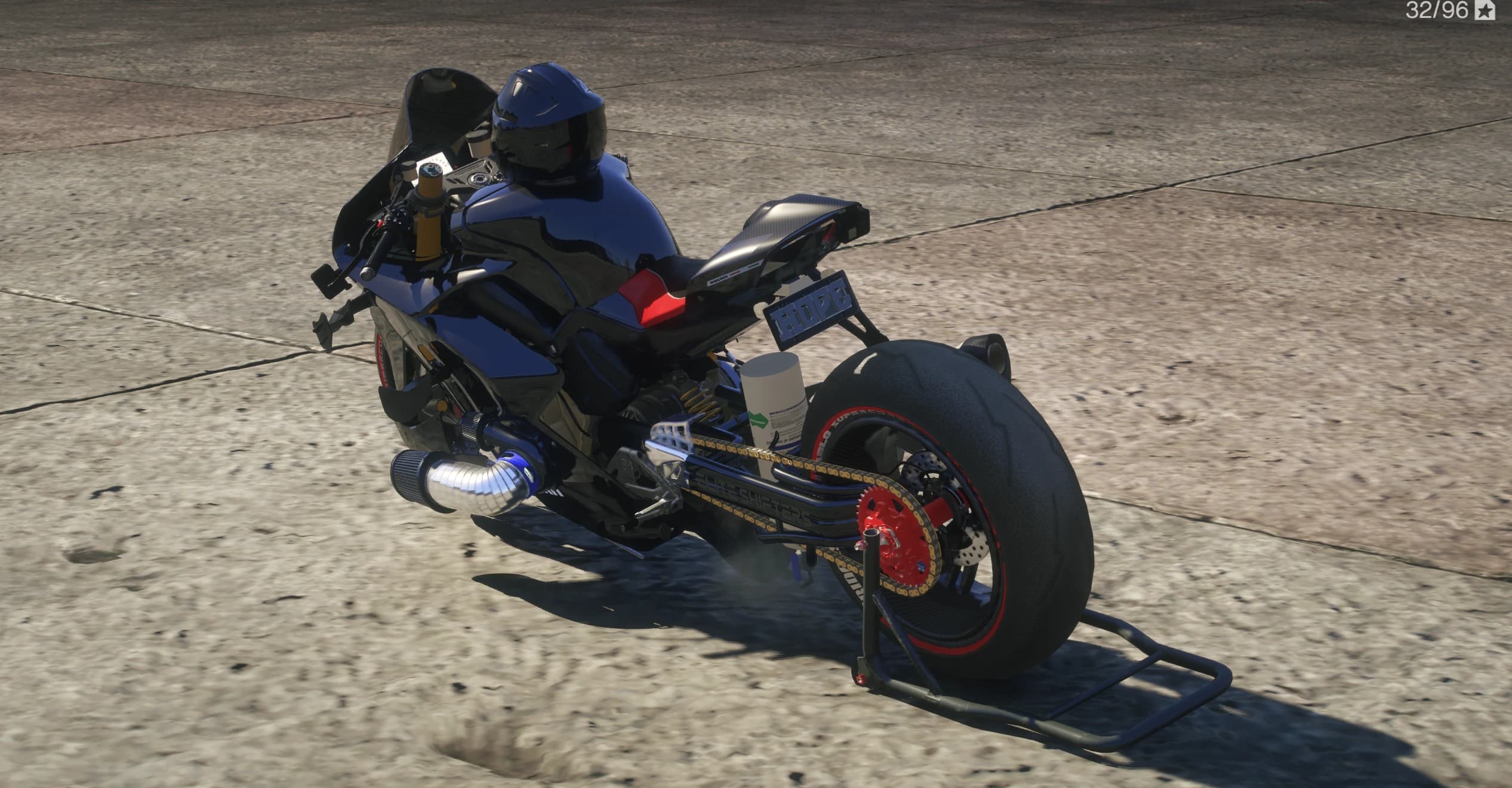 Rear three quarter view showing the HOPE plate, white bottle by the rear shock, red sprocket, slick rear tyre and carbon tail on a paddock stand