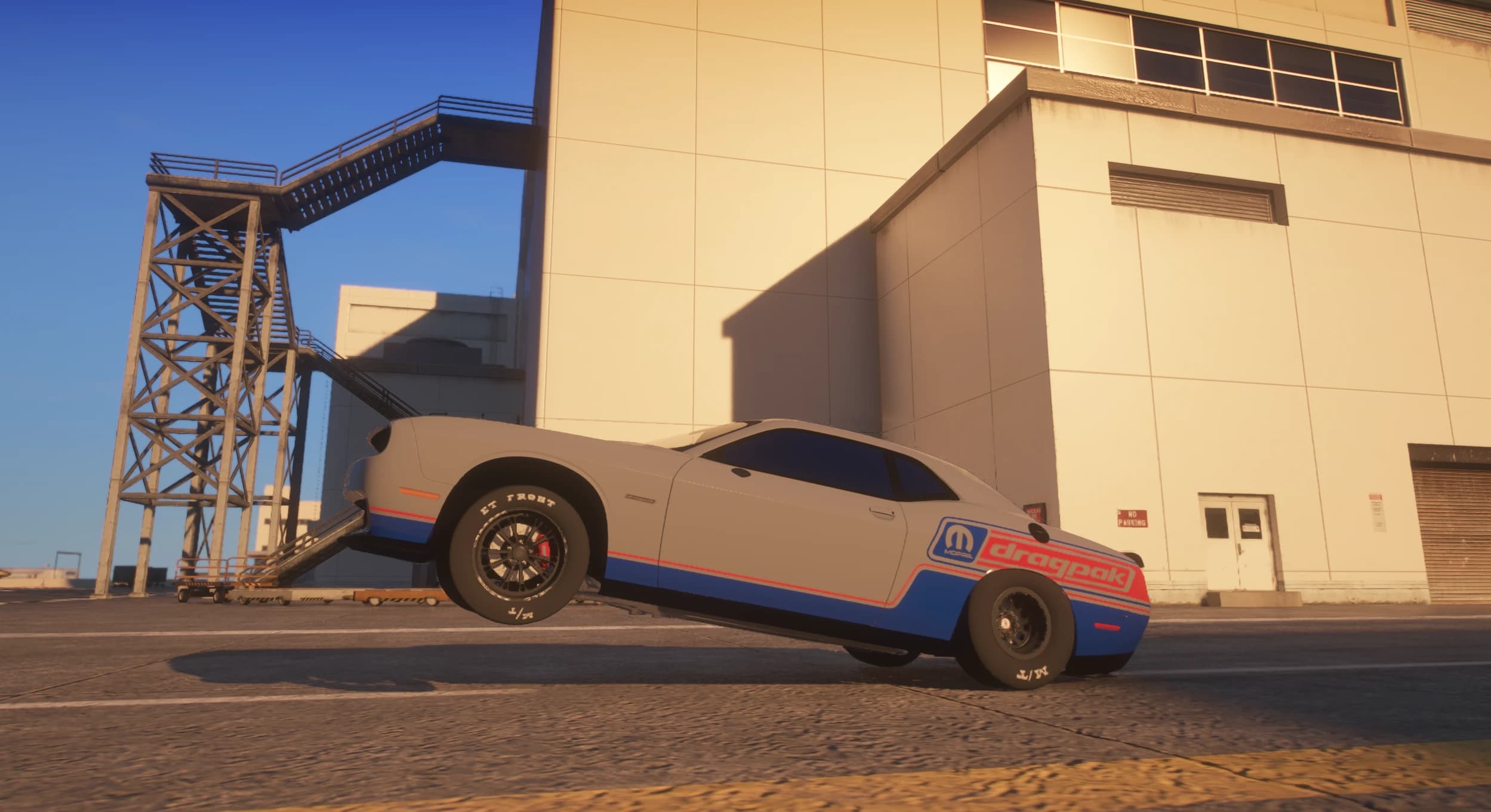 Side view of the Challenger mid wheelie with both front wheels off the ground beside an industrial building