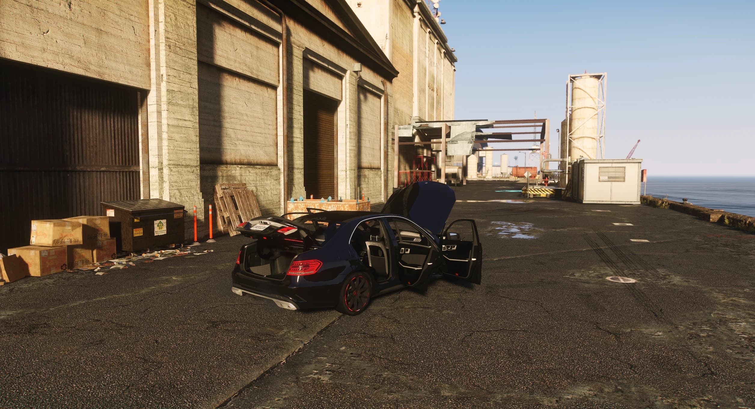 High-angle view of the black E63 with its boot and doors open on a dockside, showing the interior and boot space