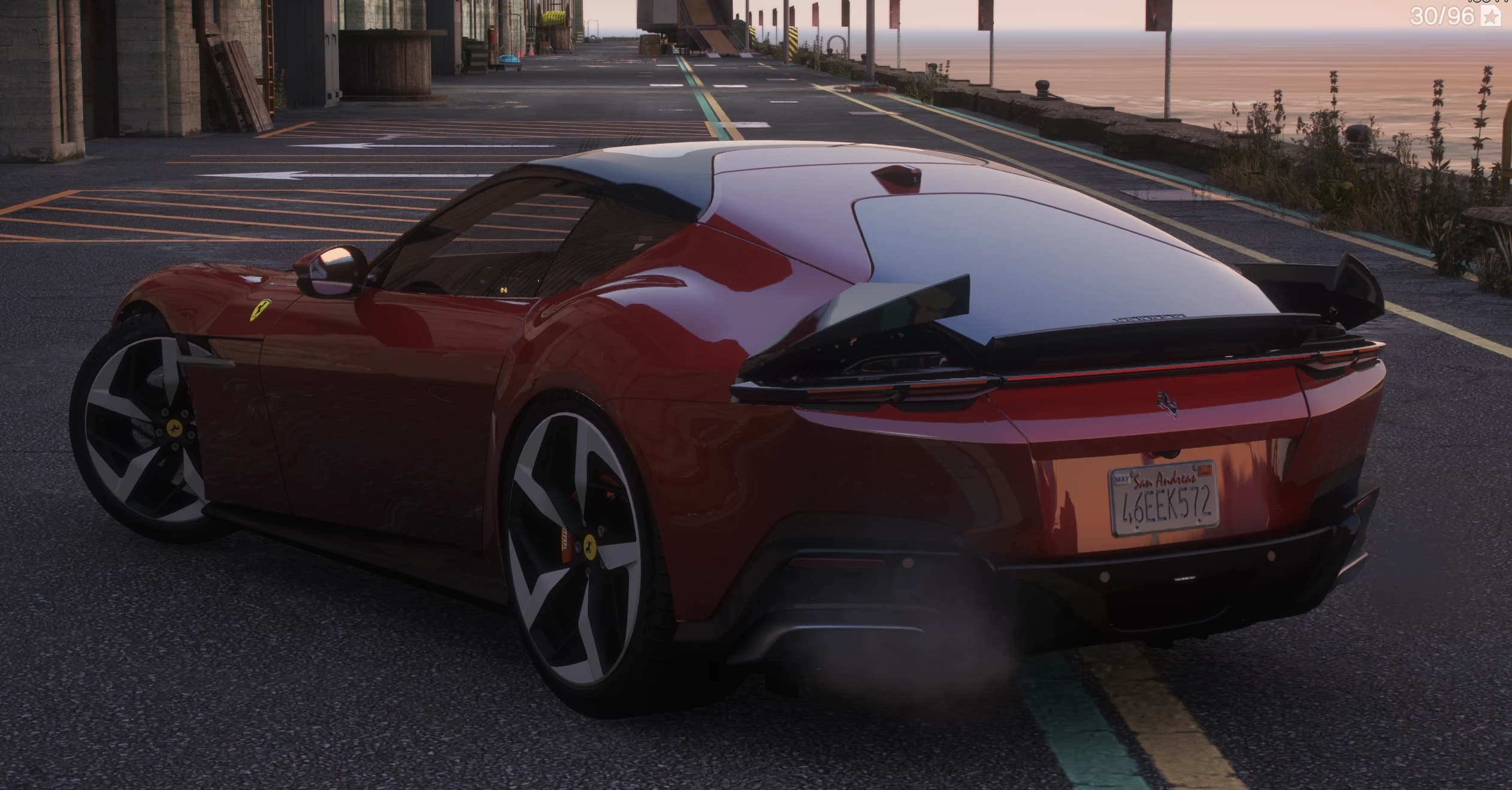 Rear three quarter view at sunset on the harbour front with the animated spoiler flaps raised over the full-width tail light bar