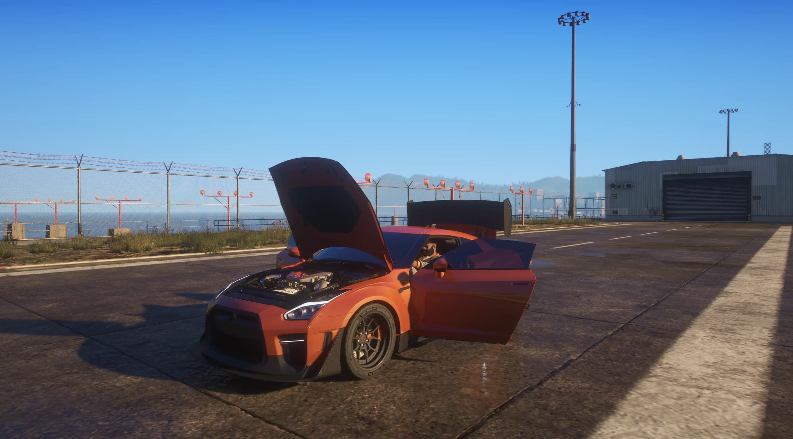 The GT-R parked on airfield concrete with the hood open over the twin turbo V6 and both doors open