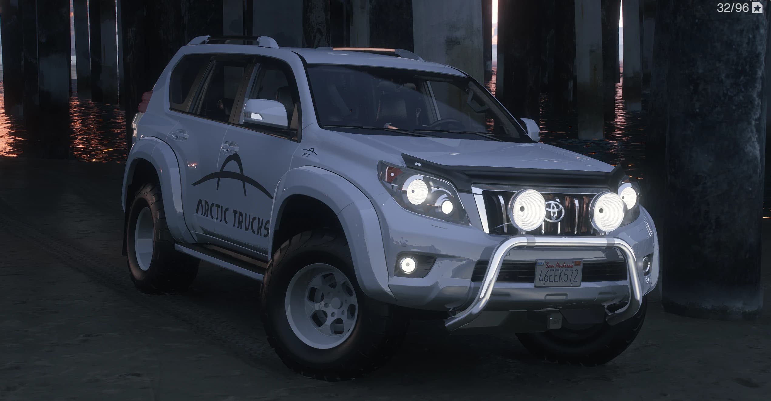 Front three quarter of the white Land Cruiser Prado with a bull bar, spot lights, snorkel and the Arctic Trucks livery