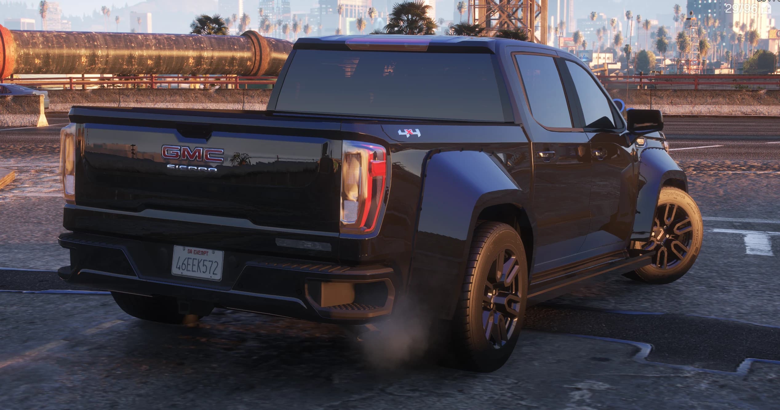 Rear three-quarter of the GMC Sierra showing the GMC SIERRA tailgate lettering, a 4x4 bed decal, widebody rear fenders and the Los Santos skyline behind