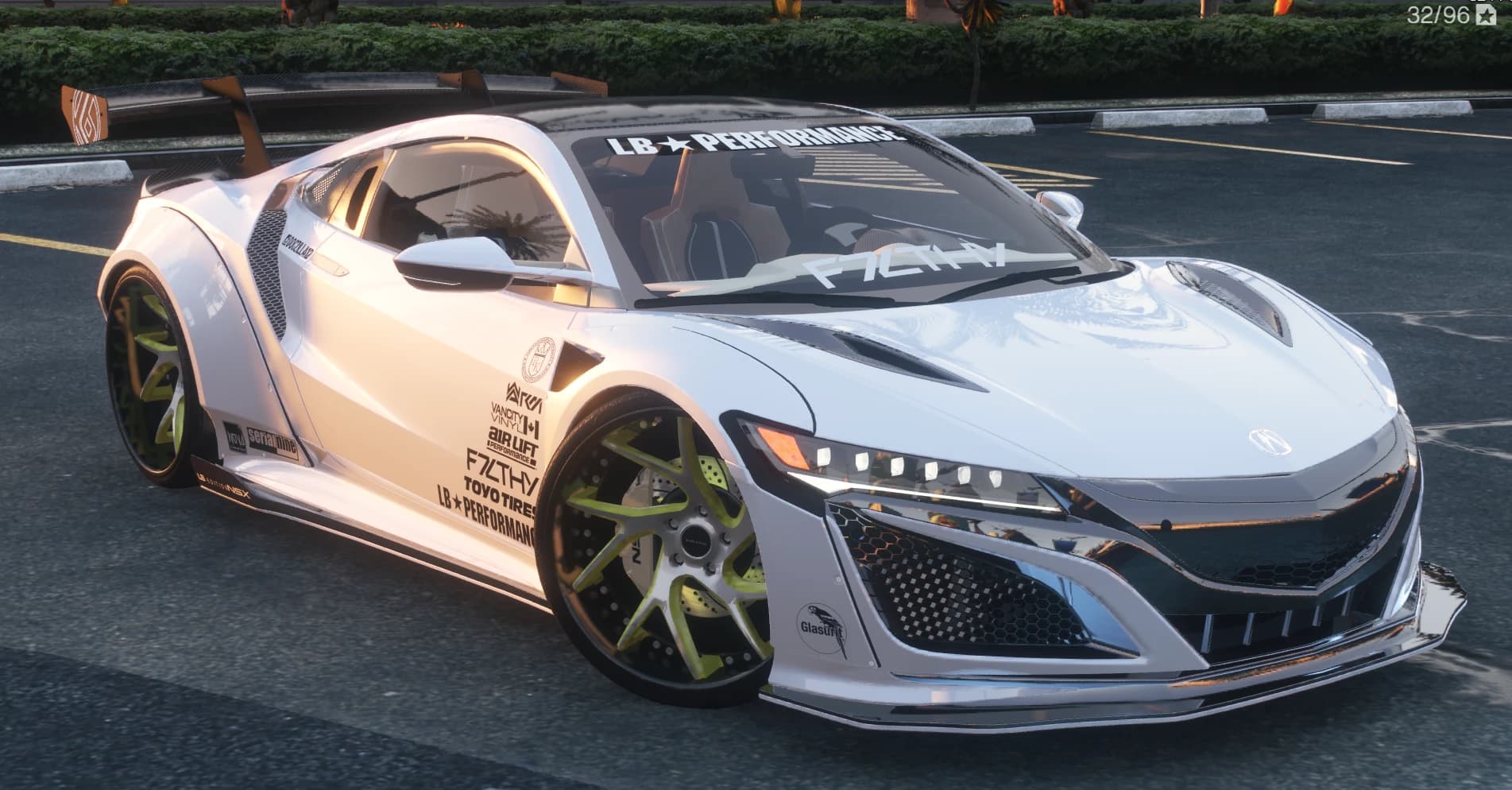Front three quarter view of the white widebody NSX with the LB Performance windshield banner, sponsor stack on the door and lime green spoke wheels