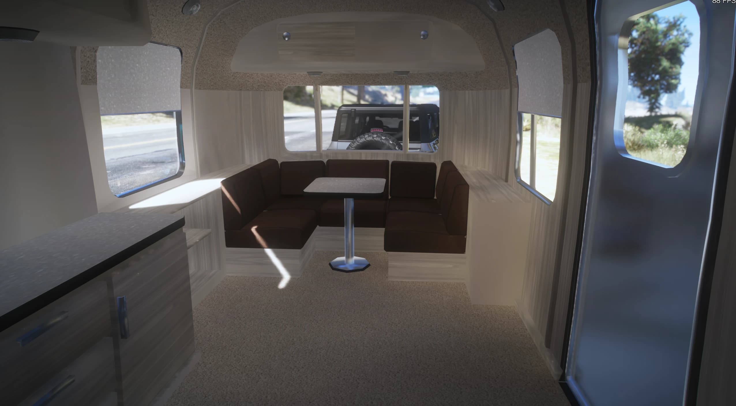 Modelled interior of the White Liner with a brown wraparound dinette around a pedestal table, a kitchen counter and curtained windows