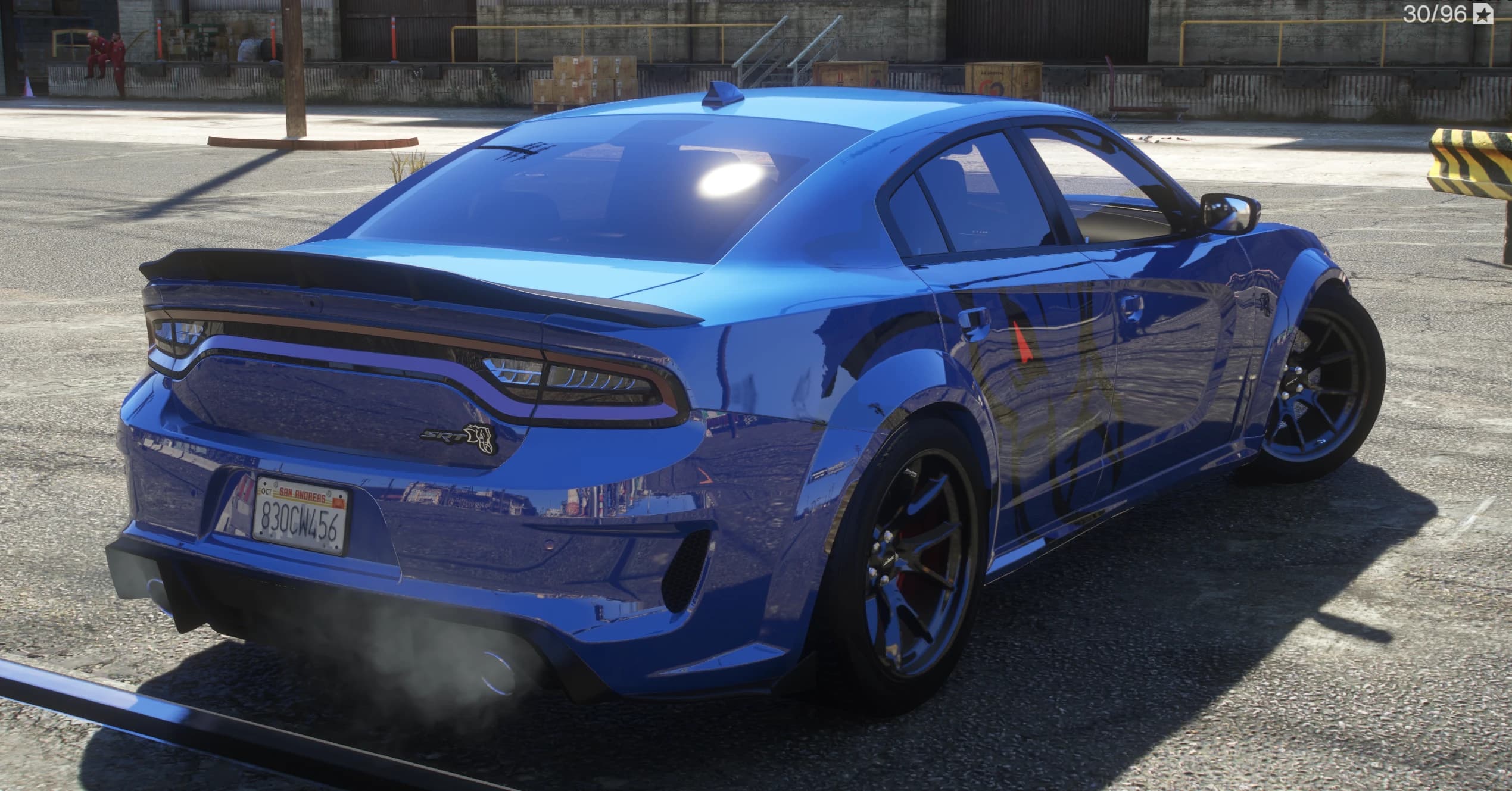 Rear three-quarter of the blue Charger with its full-width LED taillight bar, SRT Hellcat badge, ducktail spoiler and exhaust smoke, wearing a San Andreas plate reading 830CW456 over widebody fenders