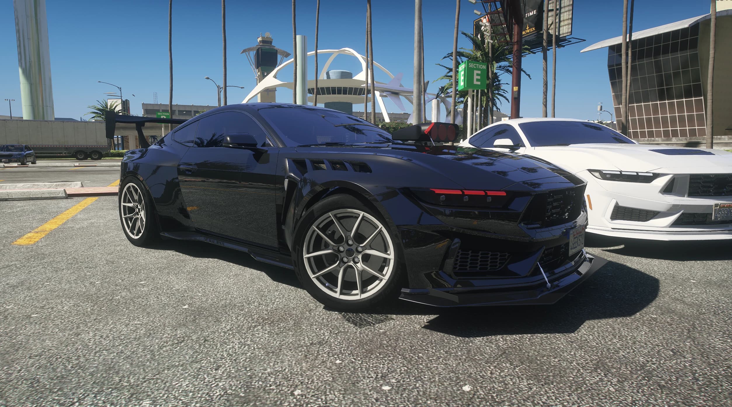 Black stanced 2025 Mustang with a hood blower, splitter rods and fender vents parked at the airport