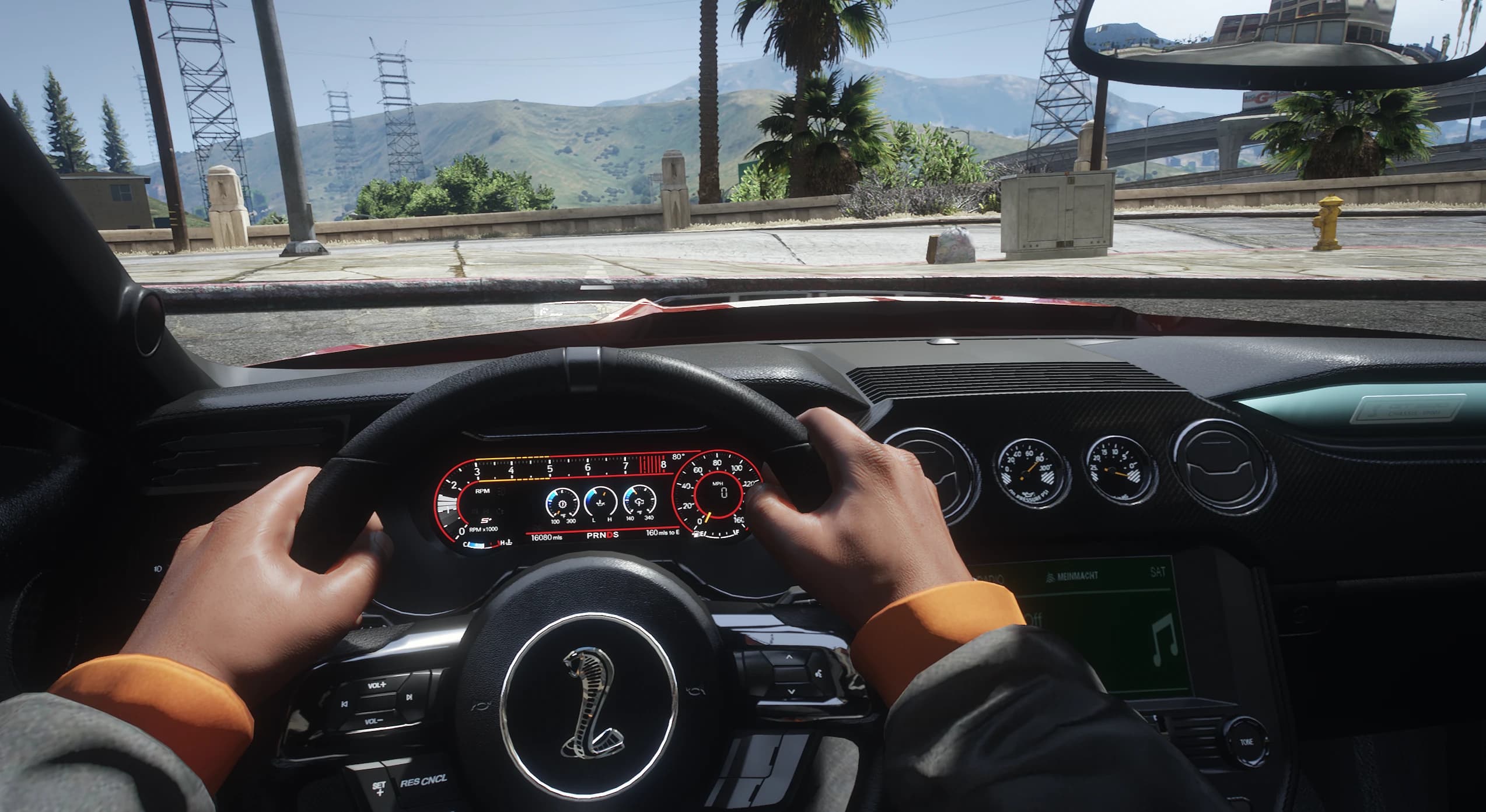 First person view behind the wheel with the digital instrument cluster, auxiliary dash gauges and the cobra on the steering wheel