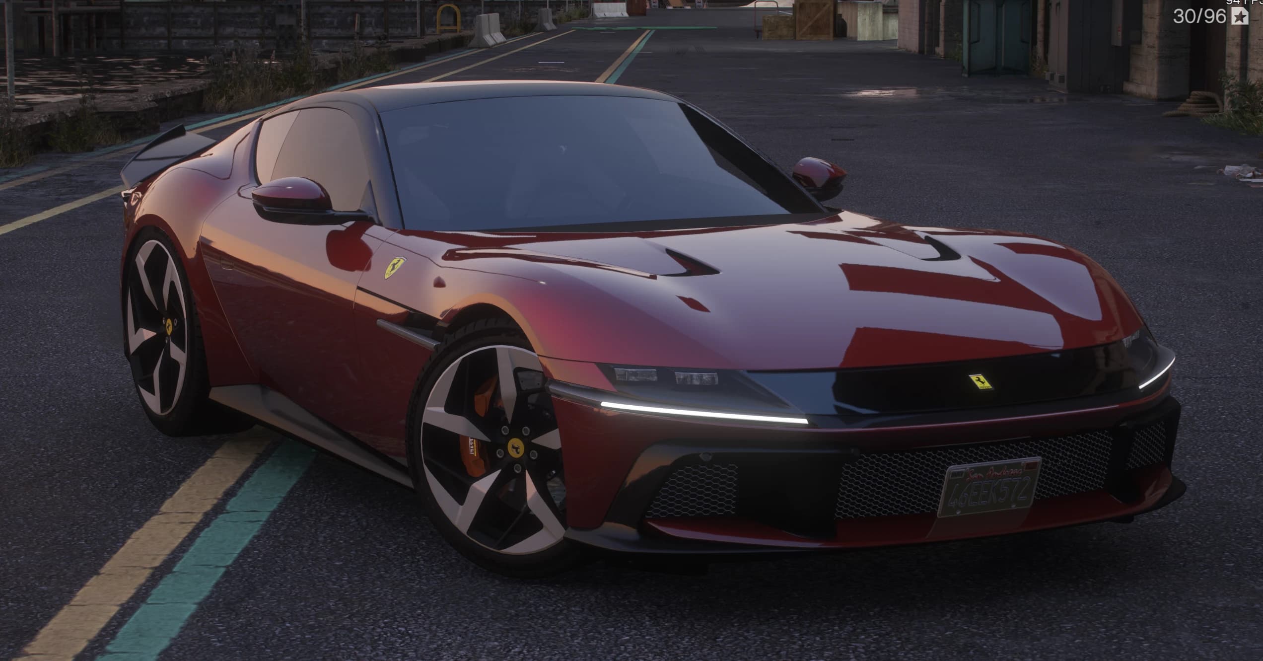 Front three quarter view of the dark red Ferrari 12 Cilindri in an industrial dock area, showing the black nose band with slim LED daytime running lights