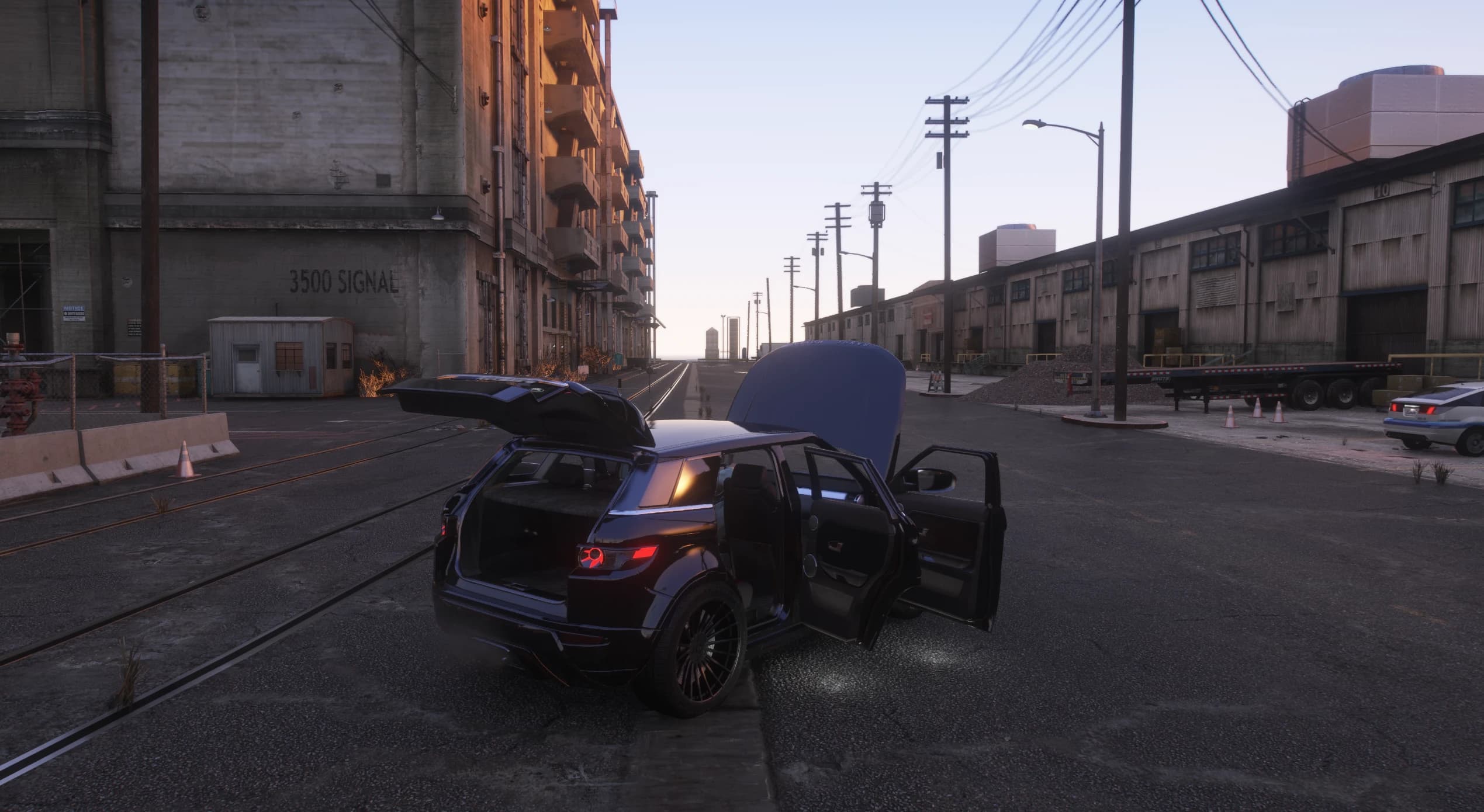 The Evoque parked on a dockside street at dusk with the tailgate, bonnet and doors open, showing the boot and the leather interior
