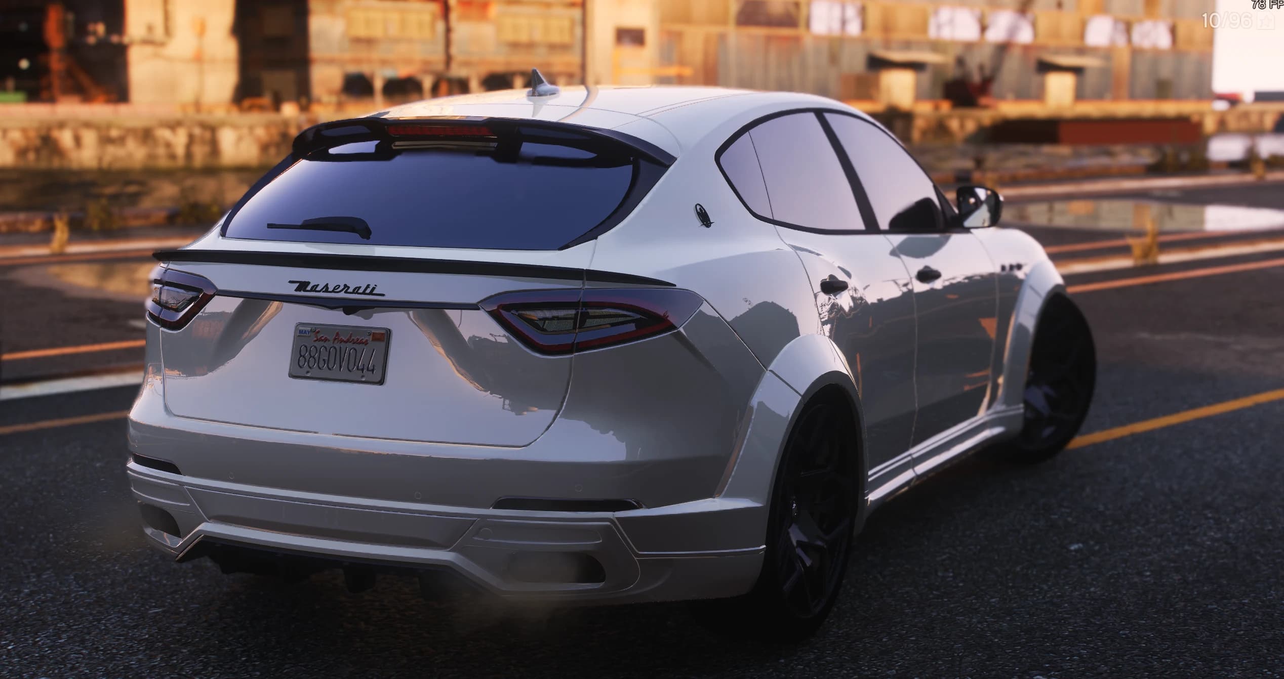 Rear three-quarter of the white Levante at sunset showing the roof spoiler, the black lip on the tailgate, the Maserati lettering and the San Andreas plate 88GOV044