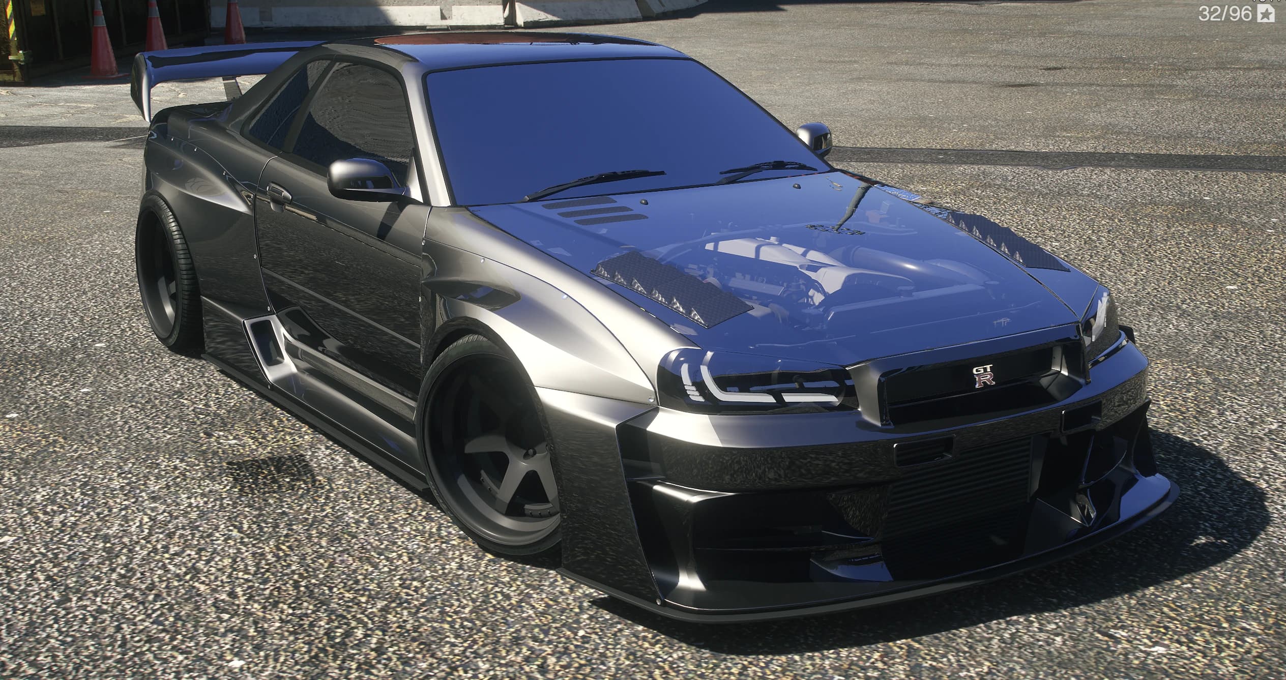 Front three quarter of the widebody Skyline R34 GT-R with the exposed engine under a glass hood and deep splitter