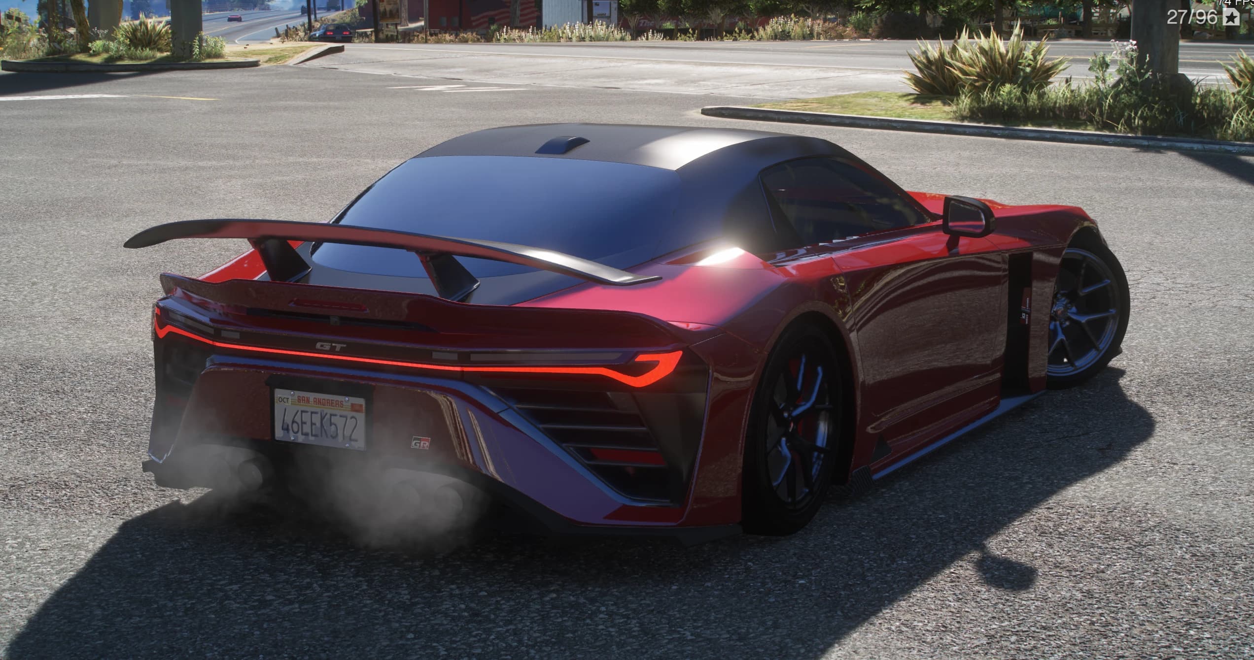 Rear three-quarter of the red GR GT with a full-width light bar, the GT badge, a large rear wing and a quad exhaust, on a road
