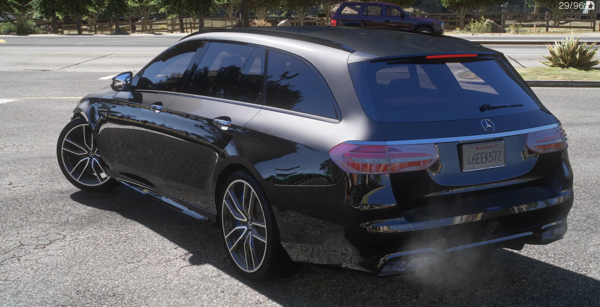 Rear three-quarter of the black E63 S wagon with the Mercedes star, the AMG badge, roof rails and quad exhaust