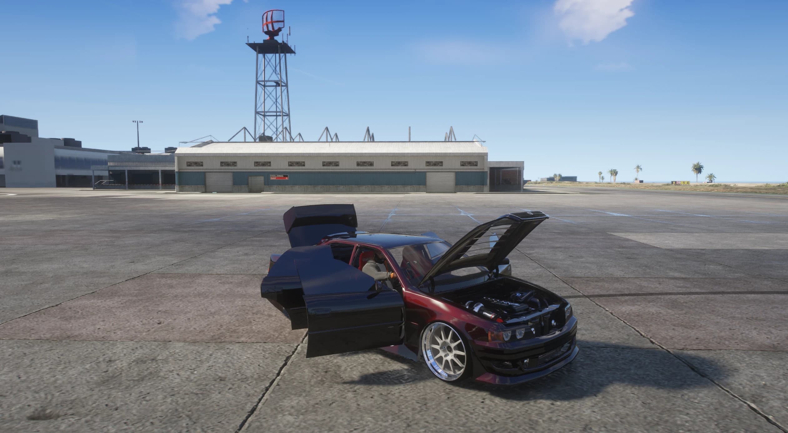 Dark red Chaser on the airport tarmac with doors, bonnet and boot open, exposing the turbocharged straight-six engine