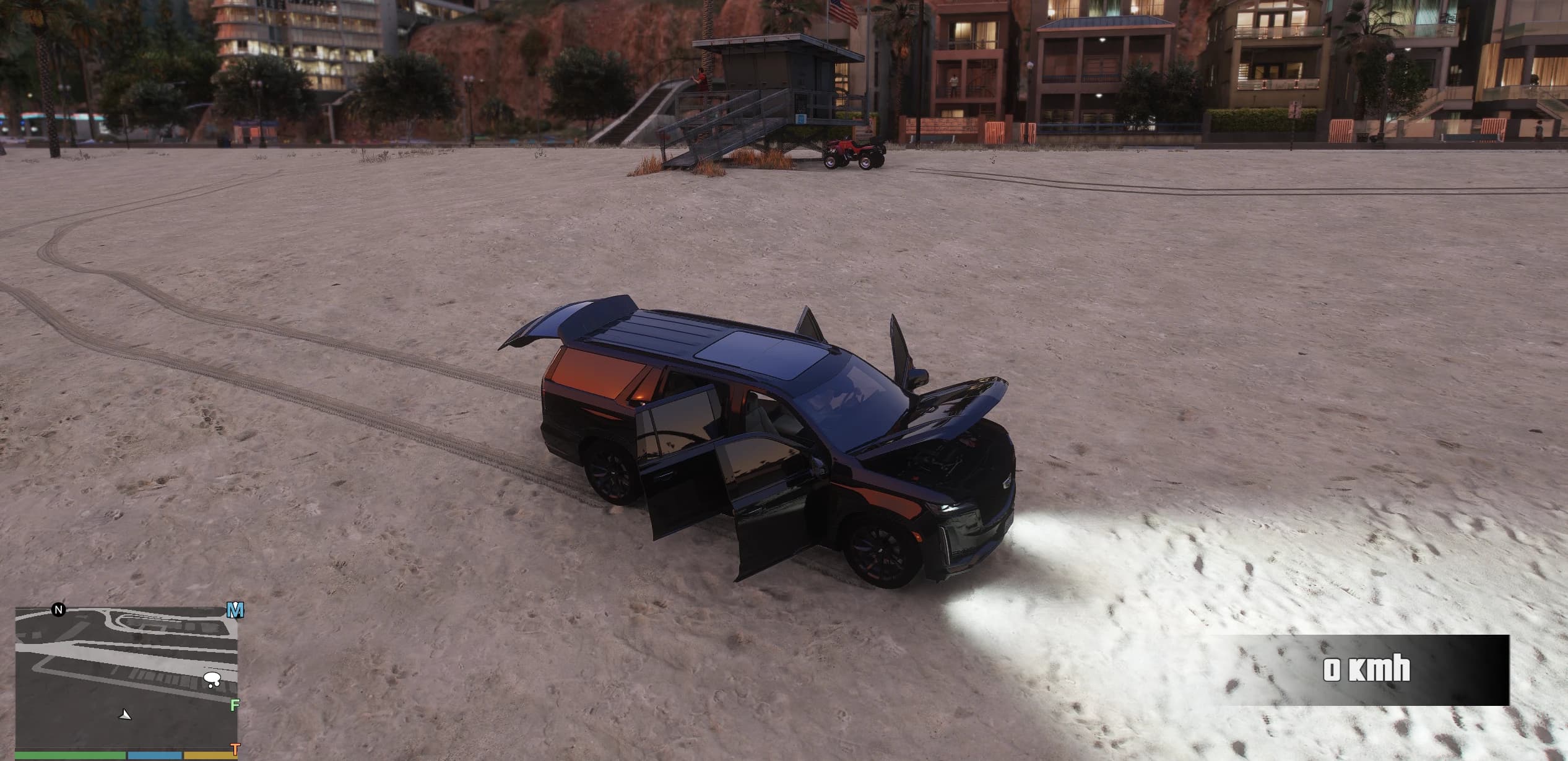 High angle of the Escalade on the sand with the hood, the two left doors and the tailgate open, the engine bay visible and the headlights throwing a beam across the beach