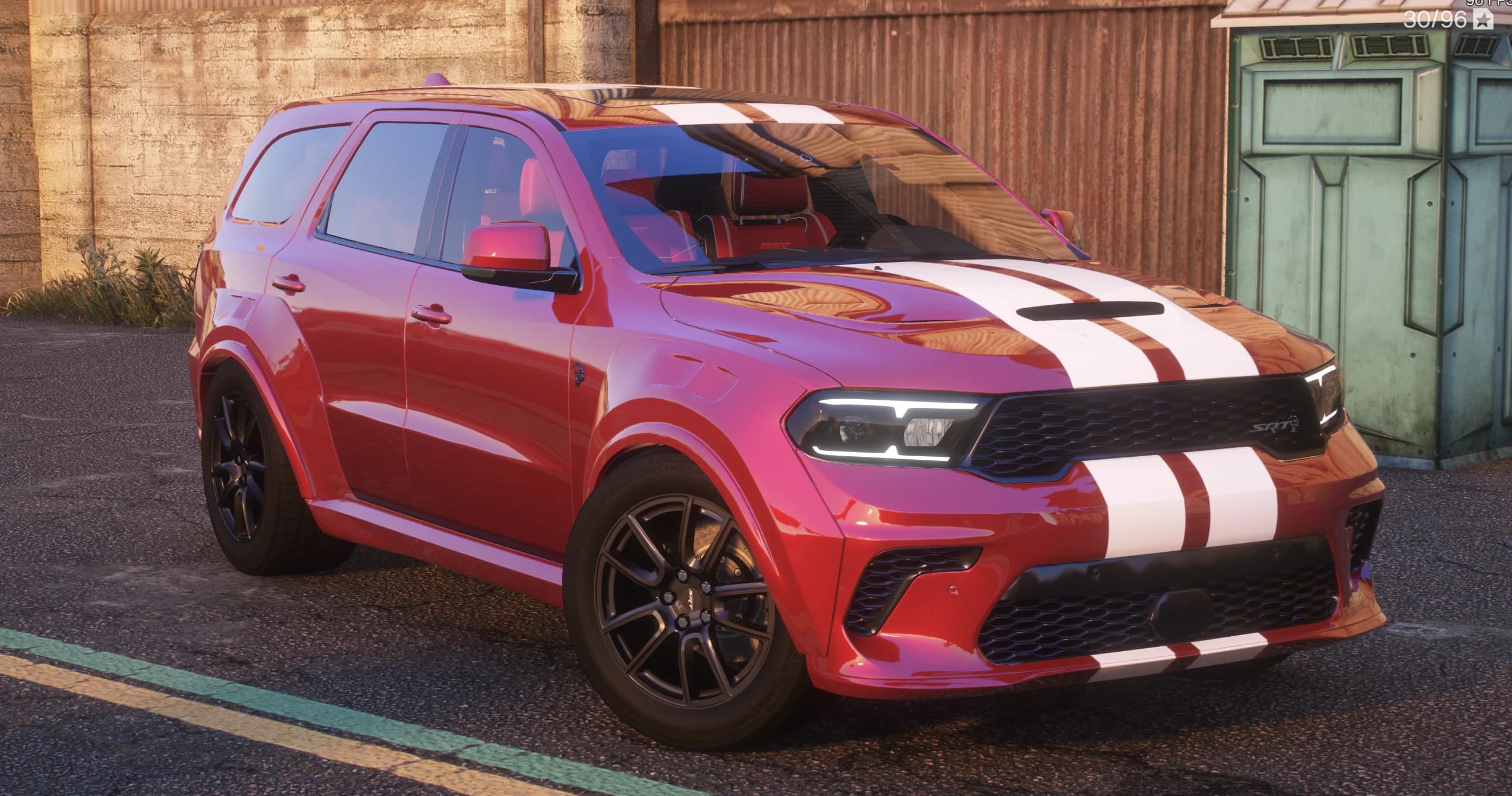 Red 2021 Dodge Durango Widebody SUV with twin white racing stripes over the roof and hood, front three-quarter view beside a green dumpster, showing the SRT grille badge, slim LED headlights and black multi-spoke wheels
